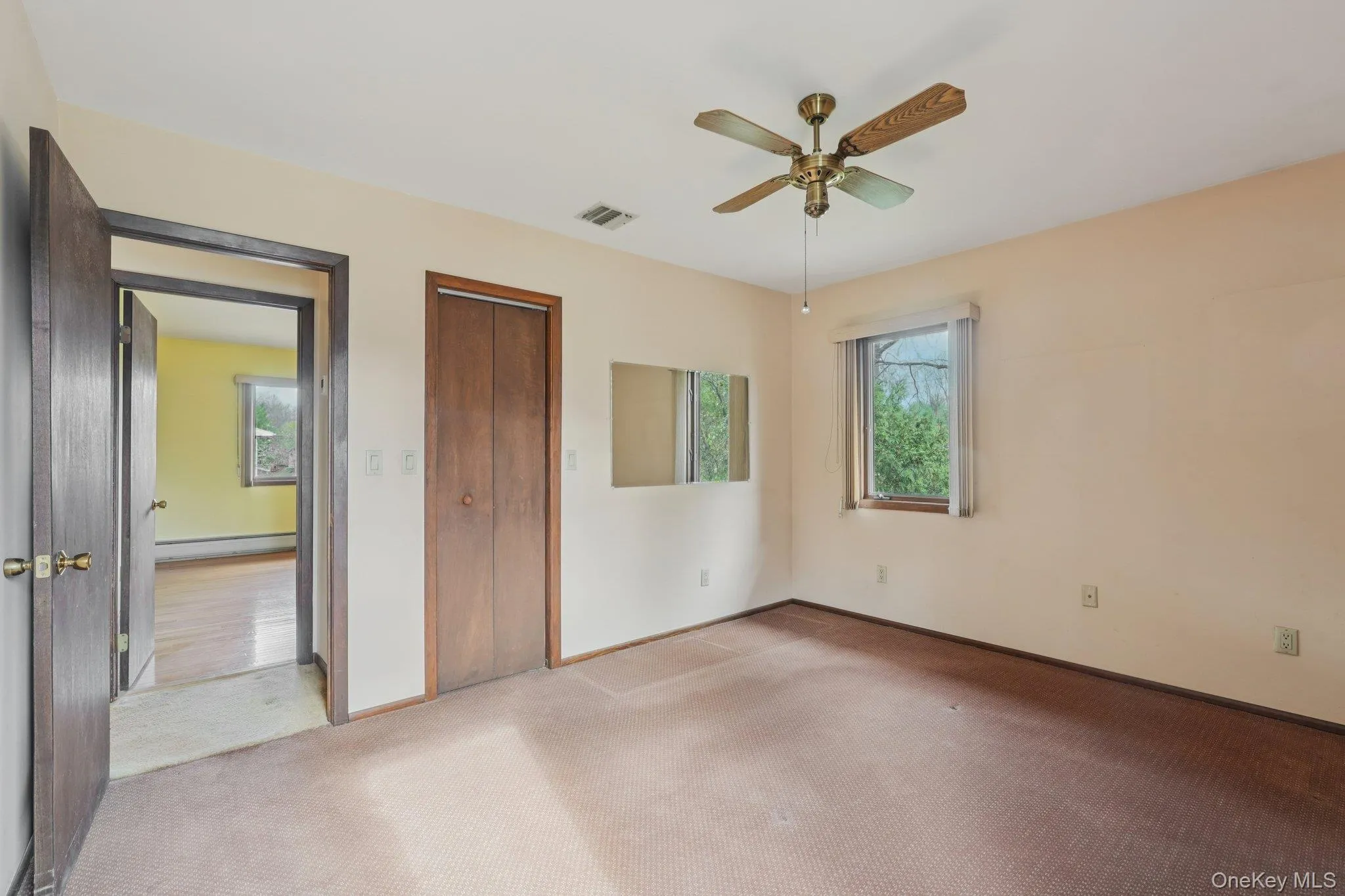 Unfurnished bedroom featuring carpet flooring, a closet, a baseboard heating unit, and ceiling fan Unfurnished bedroom featuring carpet flooring, a closet, a baseboard heating unit, and ceiling fan