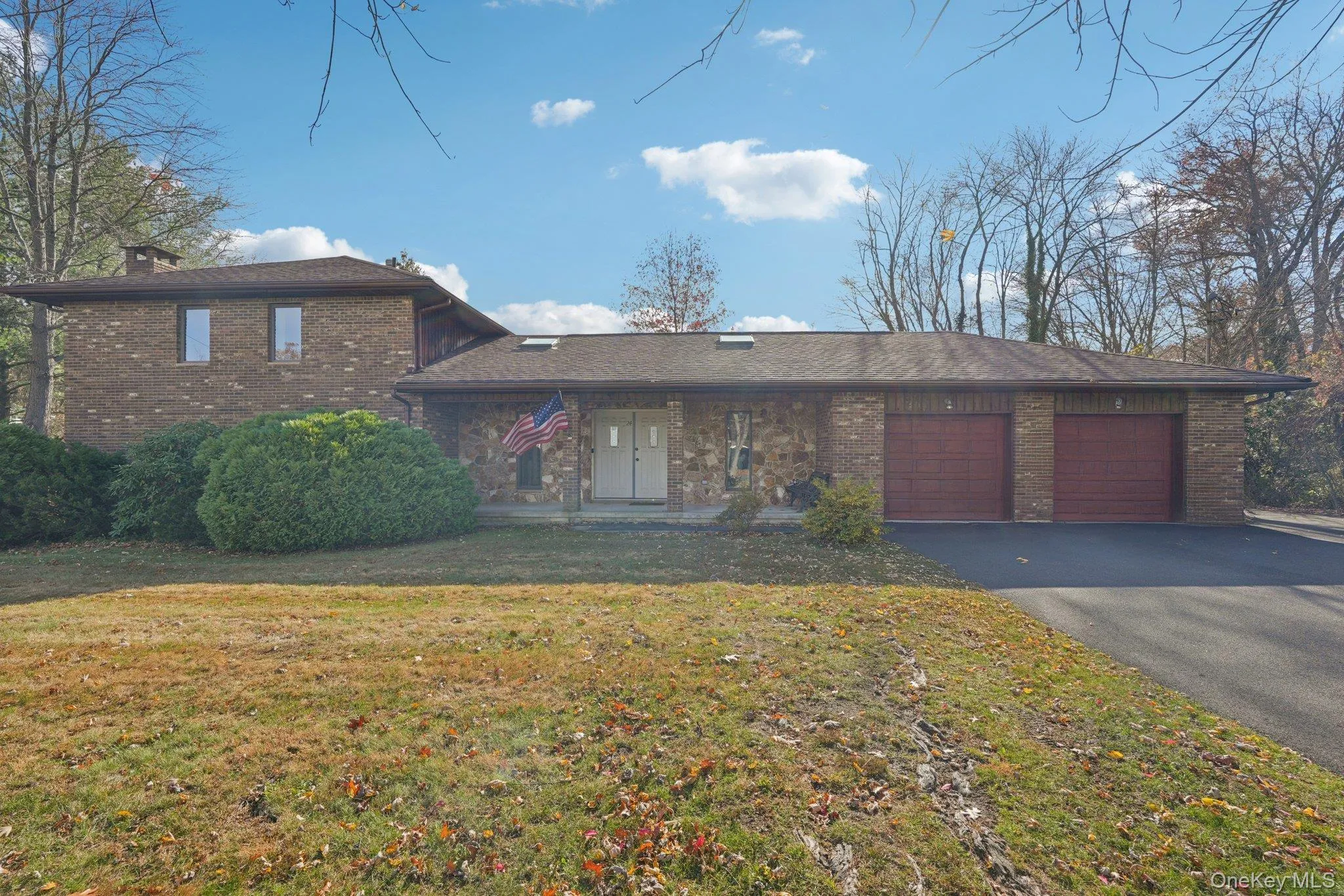 View of front of property with a garage, driveway, brick siding, a front lawn, and a chimney View of front of property with a garage, driveway, brick siding, a front lawn, and a chimney