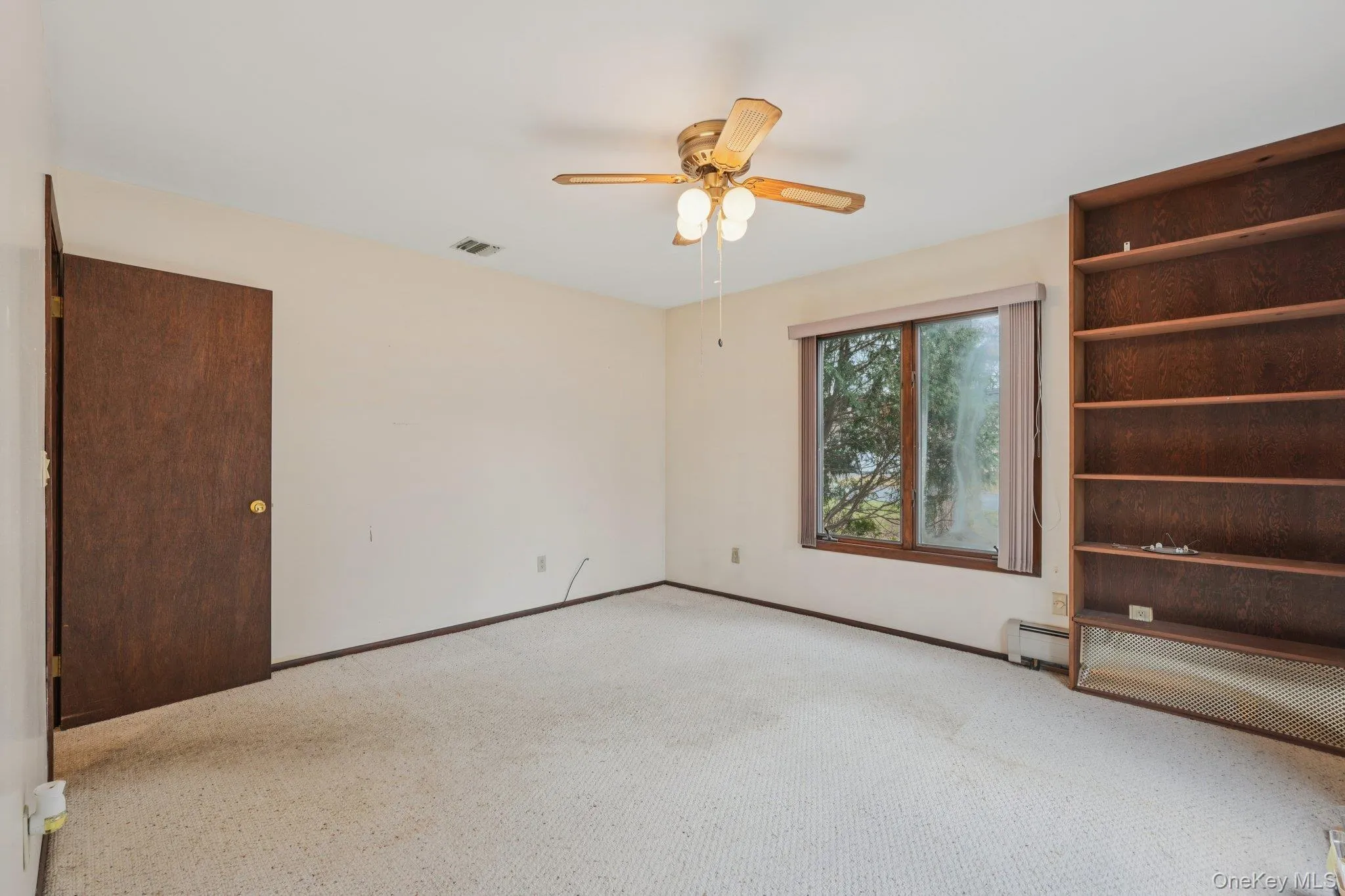 Carpeted empty room with ceiling fan and baseboard heating Carpeted empty room with ceiling fan and baseboard heating
