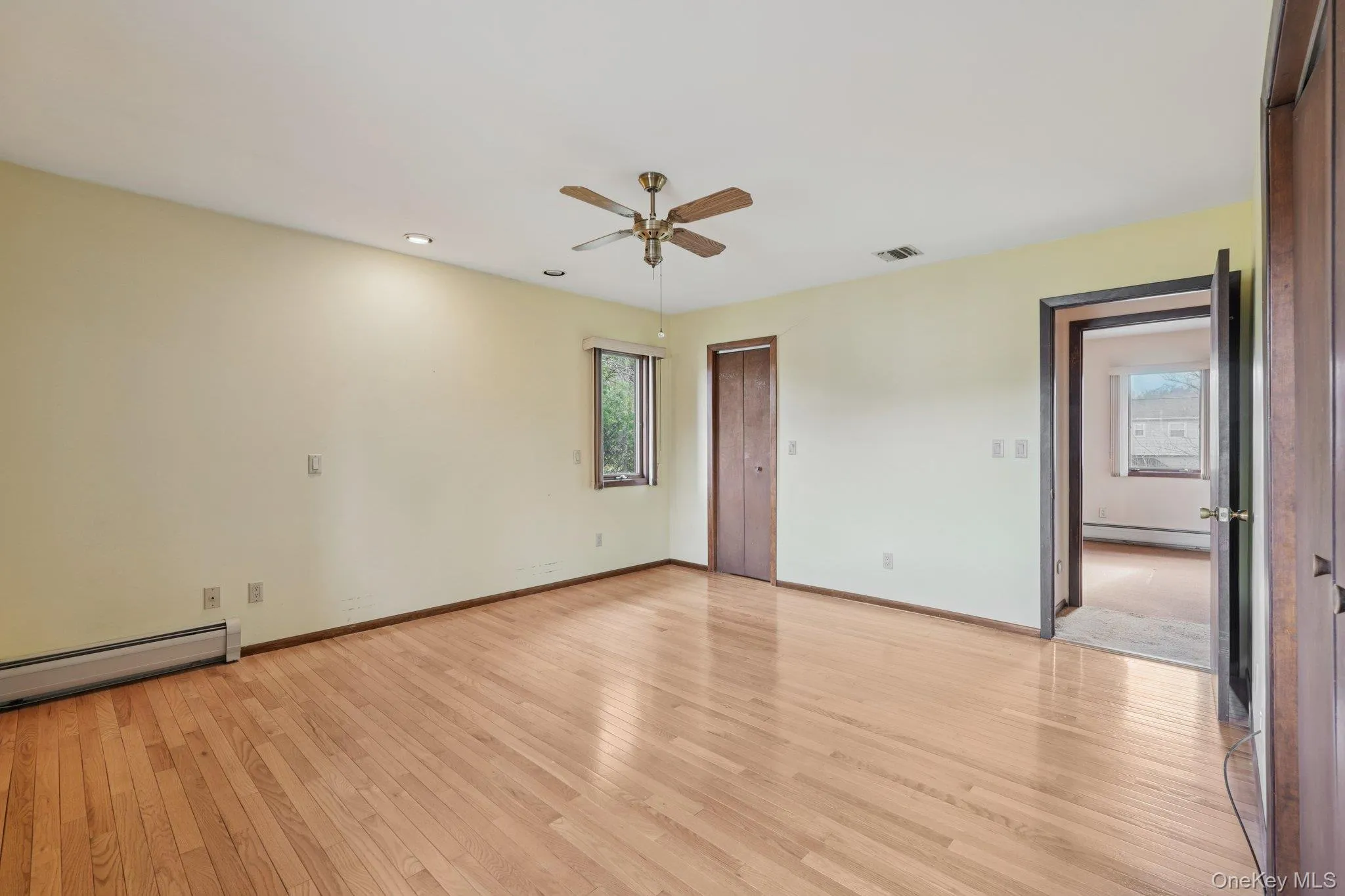 Unfurnished room with light wood finished floors, a baseboard heating unit, and a ceiling fan Unfurnished room with light wood finished floors, a baseboard heating unit, and a ceiling fan