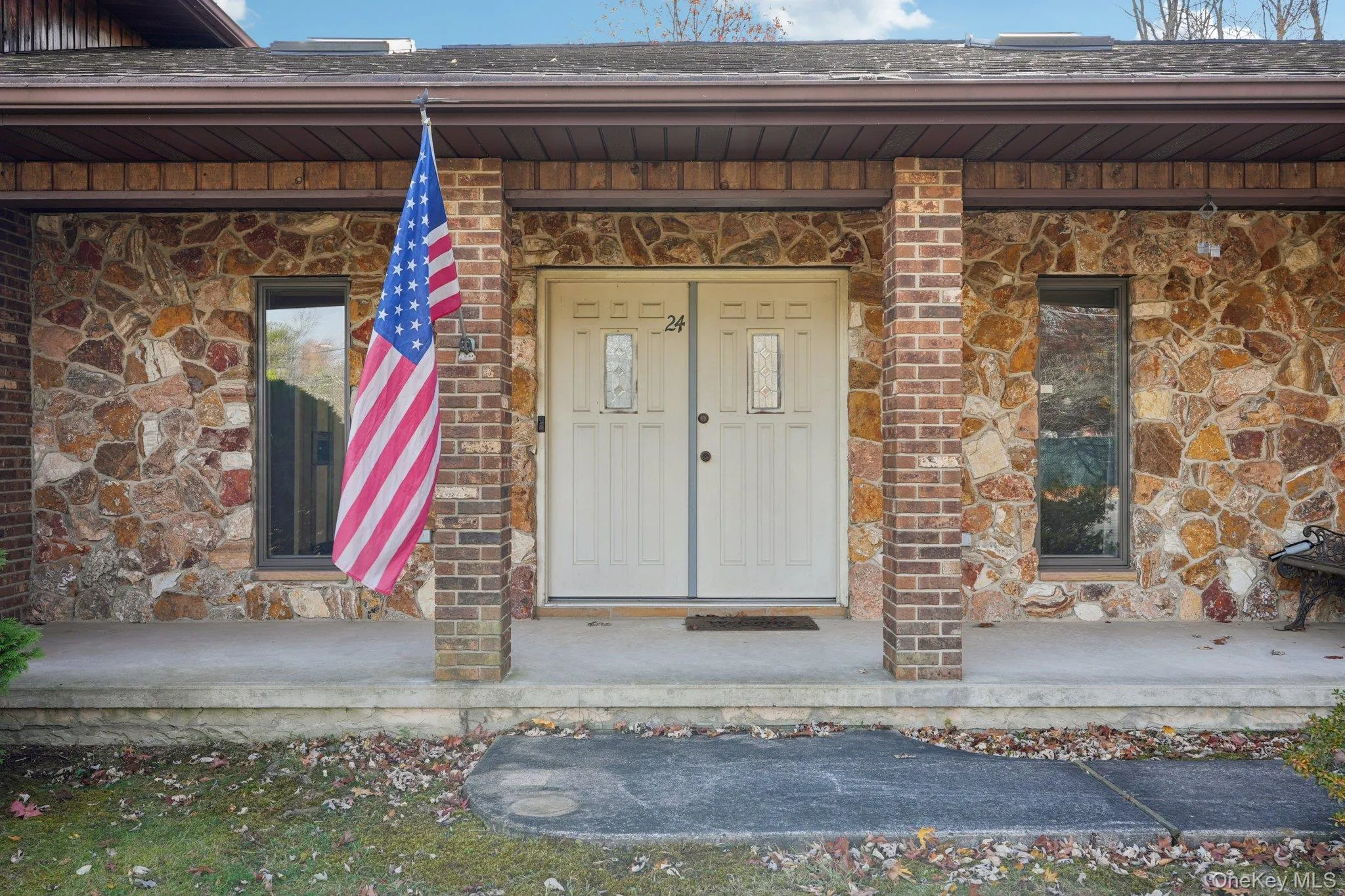 View of exterior entry featuring stone siding, a porch, and brick siding View of exterior entry featuring stone siding, a porch, and brick siding