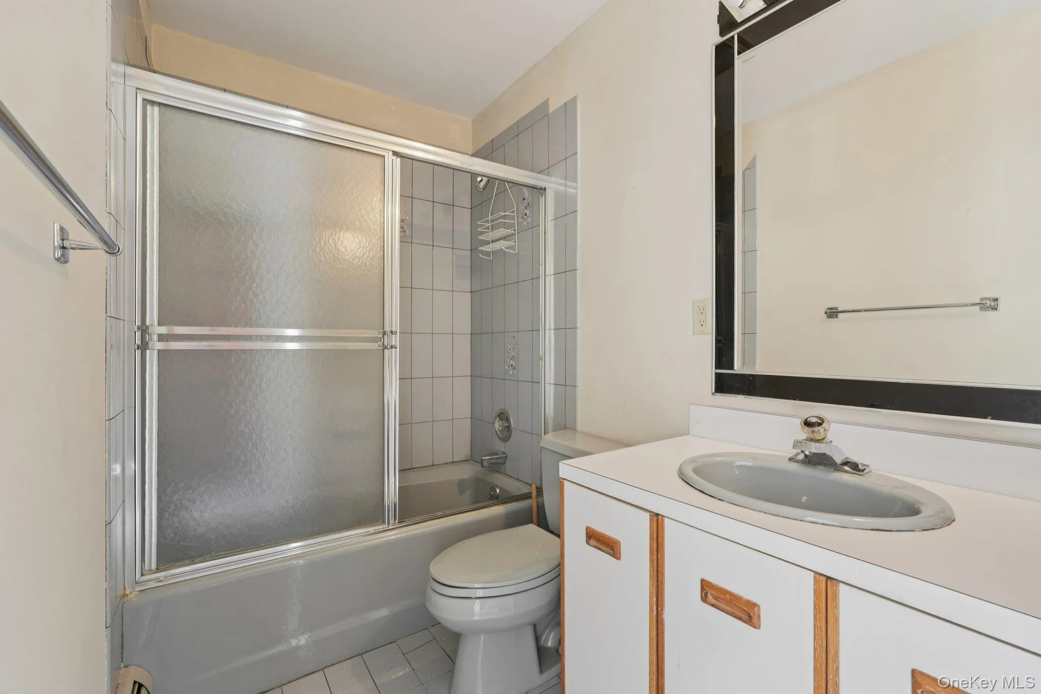 Full bathroom featuring shower / bath combination with glass door, vanity, and light tile patterned floors Full bathroom featuring shower / bath combination with glass door, vanity, and light tile patterned floors