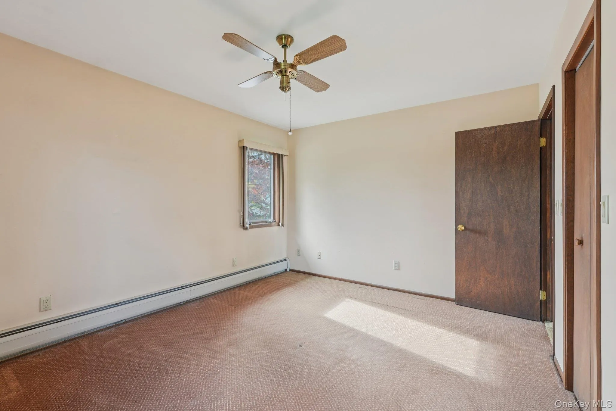 Unfurnished bedroom with a baseboard radiator, carpet floors, and ceiling fan Unfurnished bedroom with a baseboard radiator, carpet floors, and ceiling fan