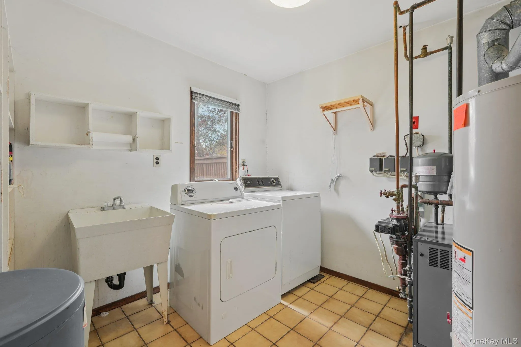 Washroom featuring water heater, light tile patterned floors, separate washer and dryer, and a heating unit Washroom featuring water heater, light tile patterned floors, separate washer and dryer, and a heating unit