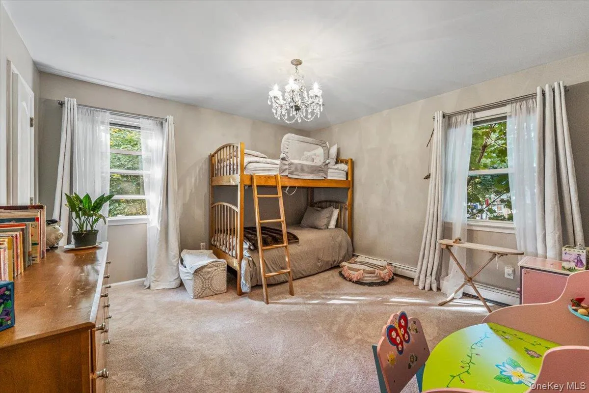 Carpeted room featuring dual windows with white trim, a crystal chandelier, and neutral painted walls Carpeted room featuring dual windows with white trim, a crystal chandelier, and neutral painted walls
