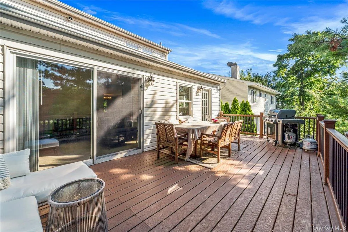 Deck with expansive seating and dinning areas accessed through glass sliding doors and separate back kitchen entrance Deck with expansive seating and dinning areas accessed through glass sliding doors and separate back kitchen entrance