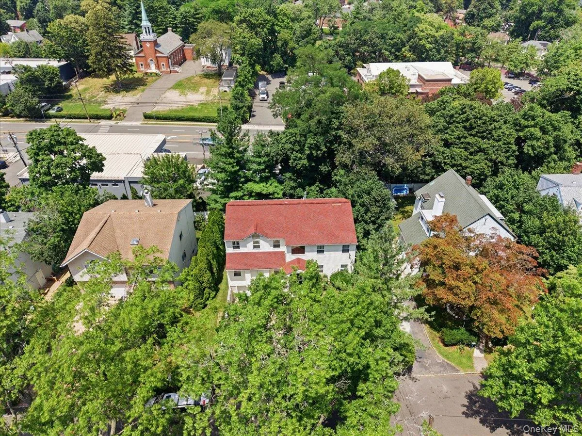 White multi-story residence featuring a red shingled roof White multi-story residence featuring a red shingled roof