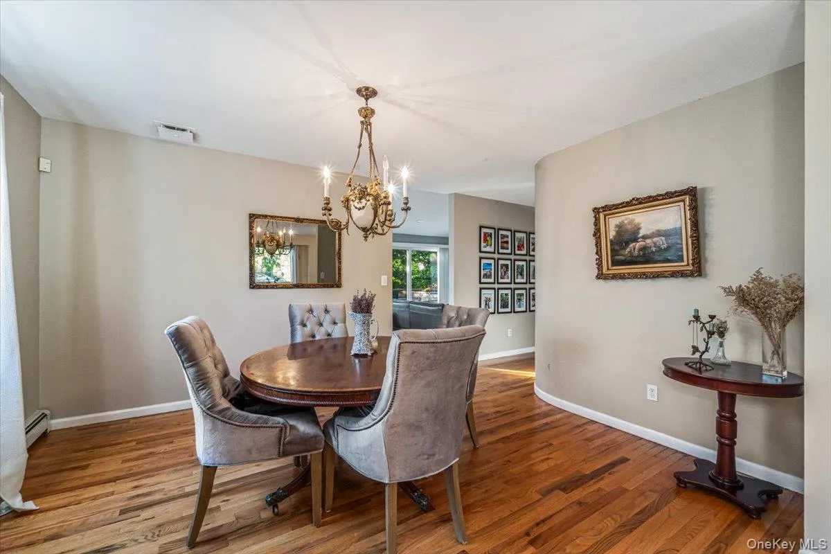 Dining area featuring hardwood flooring, a brass chandelier, a built-in wall niche, and an arched entryway Dining area featuring hardwood flooring, a brass chandelier, a built-in wall niche, and an arched entryway