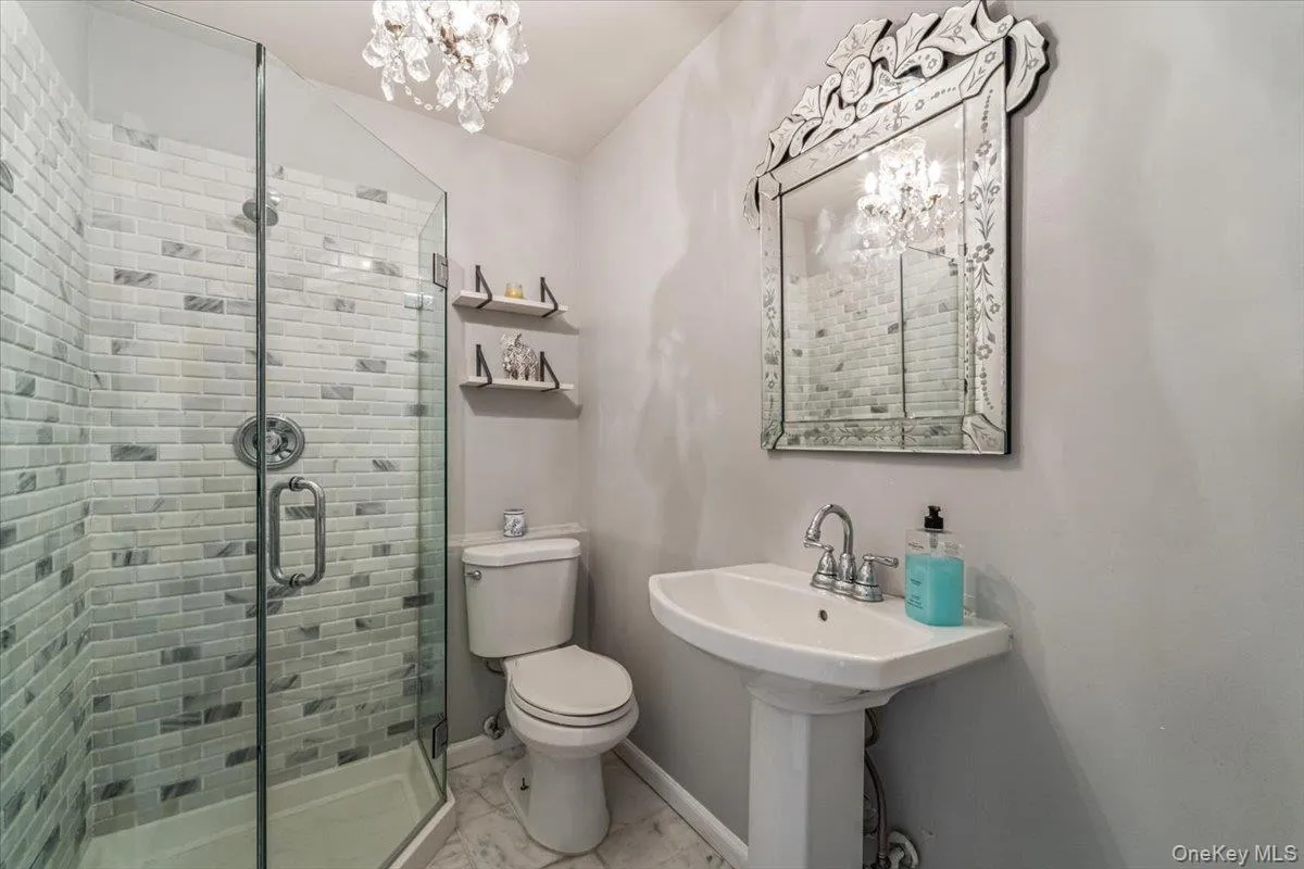 Glass-enclosed shower with subway tile surround, pedestal sink, and decorative wall mirror Glass-enclosed shower with subway tile surround, pedestal sink, and decorative wall mirror