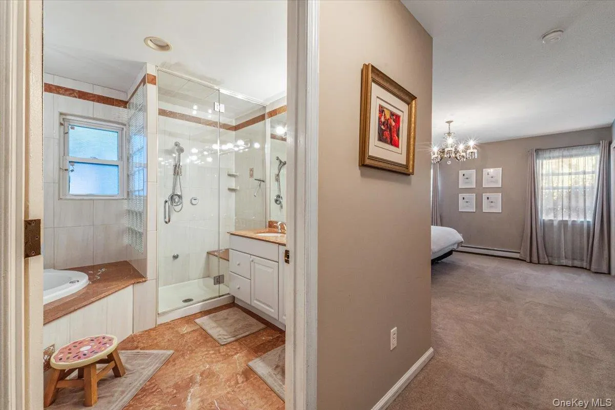 Well-appointed bathroom featuring a glass-enclosed shower, a built-in tub with tile surround, a vanity with under-sink cabinetry, and a window Well-appointed bathroom featuring a glass-enclosed shower, a built-in tub with tile surround, a vanity with under-sink cabinetry, and a window