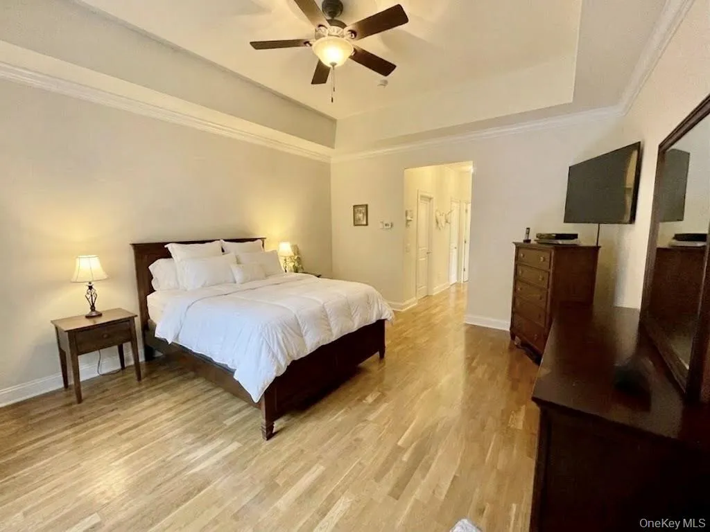 Spacious ensuite featuring wood-finish flooring and a tray ceiling with a ceiling fan Spacious ensuite featuring wood-finish flooring and a tray ceiling with a ceiling fan