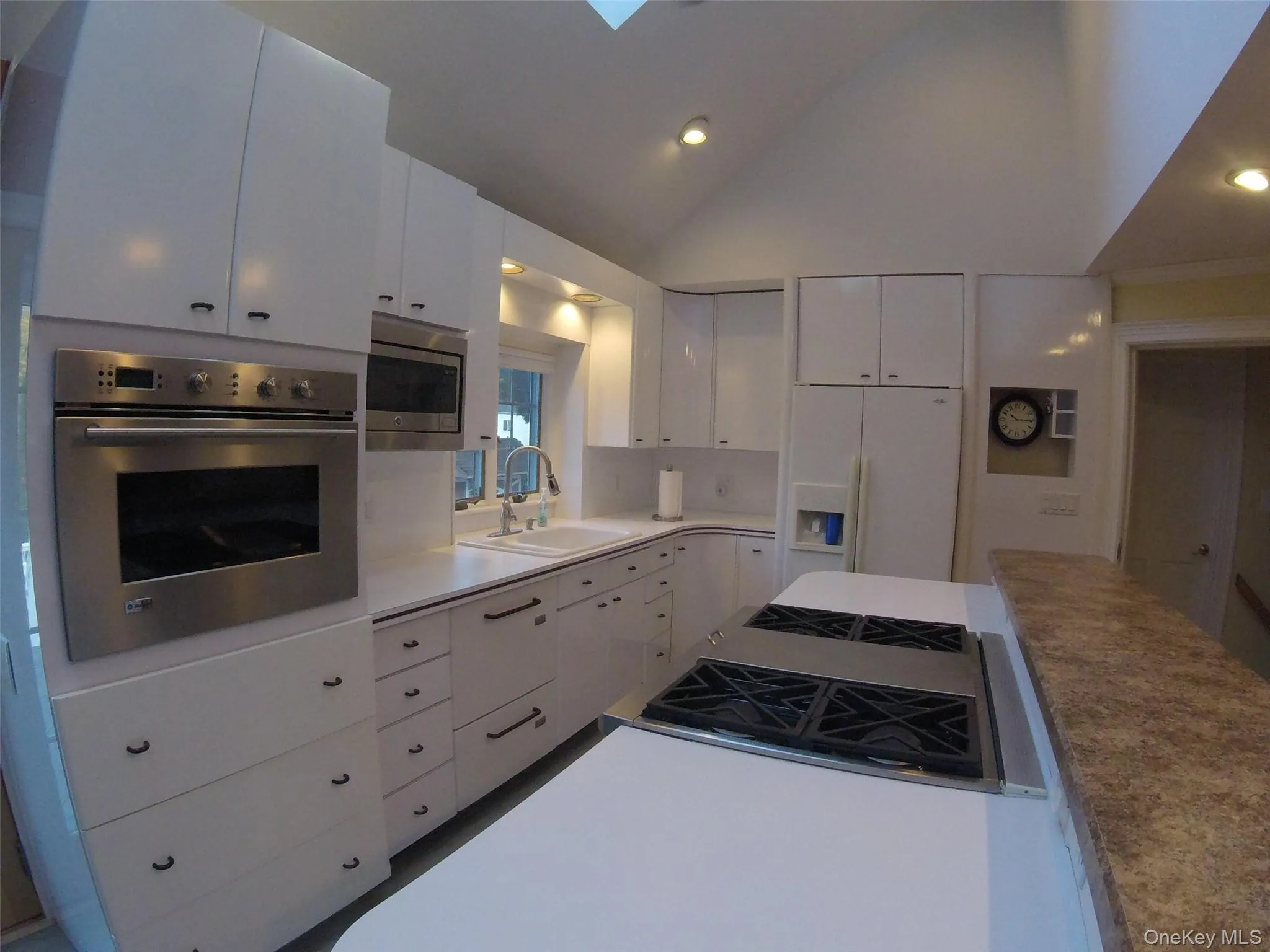 Kitchen featuring crisp white cabinetry, stainless steel appliances including a built-in oven and microwave, and a gas cooktop Kitchen featuring crisp white cabinetry, stainless steel appliances including a built-in oven and microwave, and a gas cooktop