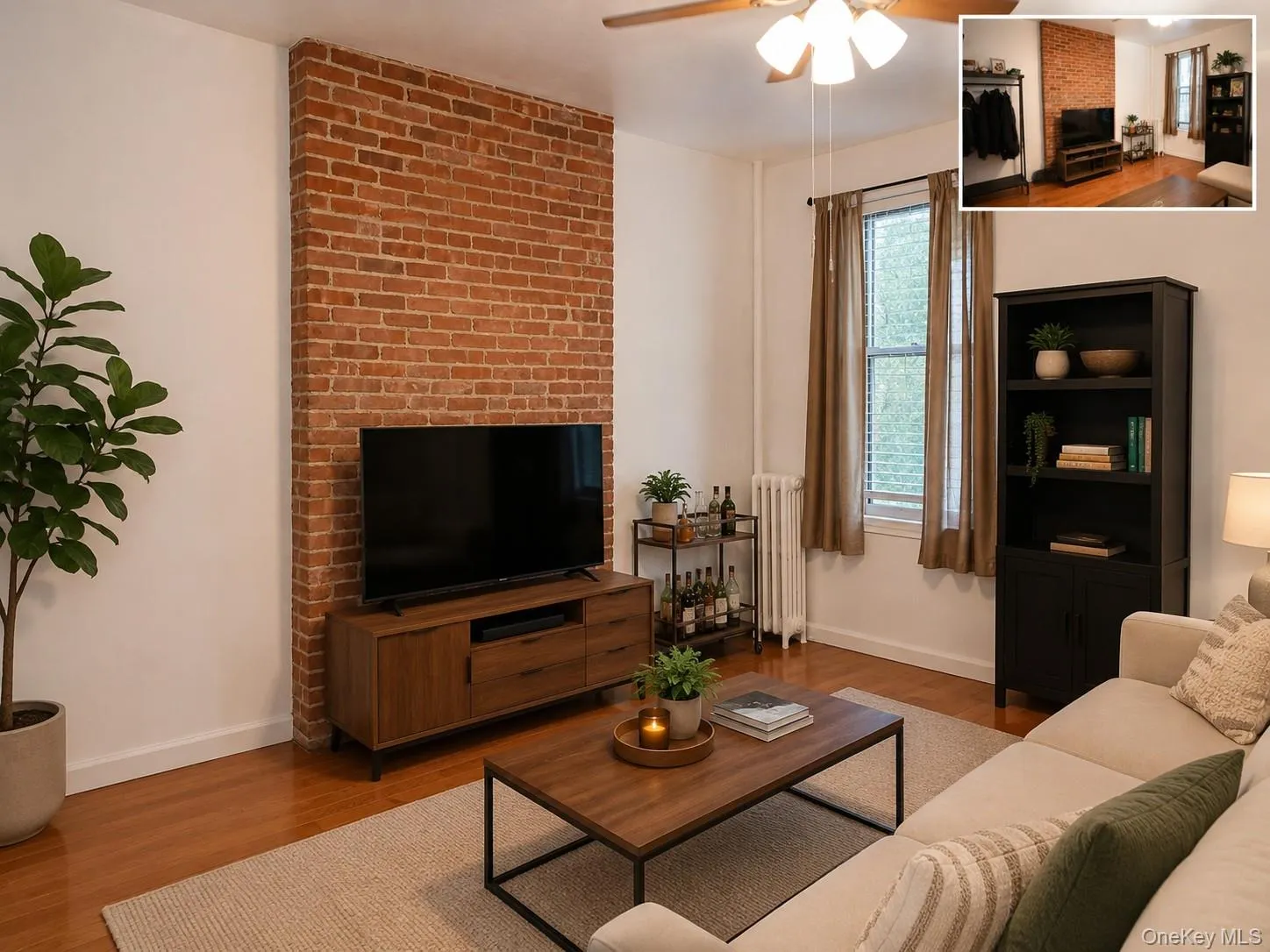 Exposed brick accent wall with wood-finish flooring, ceiling fan, and window with natural light (virtually staged) Exposed brick accent wall with wood-finish flooring, ceiling fan, and window with natural light (virtually staged)