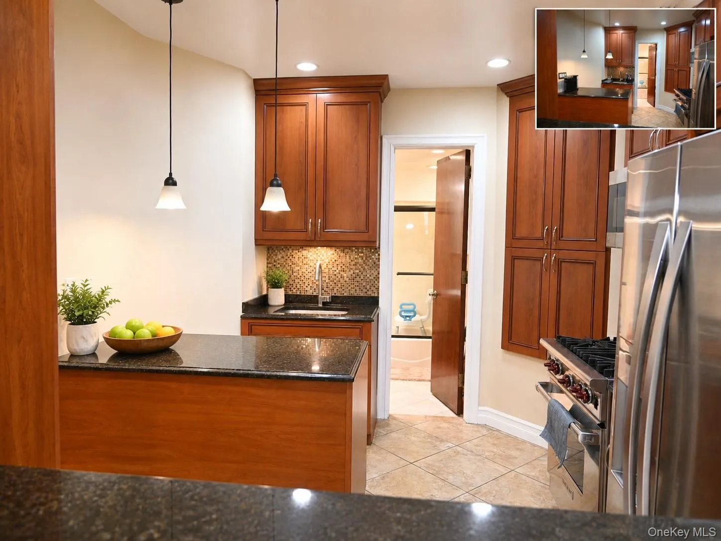 Kitchen featuring medium-tone wood cabinetry, speckled dark countertops, tile flooring, stainless steel appliances, and pendant lighting Kitchen featuring medium-tone wood cabinetry, speckled dark countertops, tile flooring, stainless steel appliances, and pendant lighting