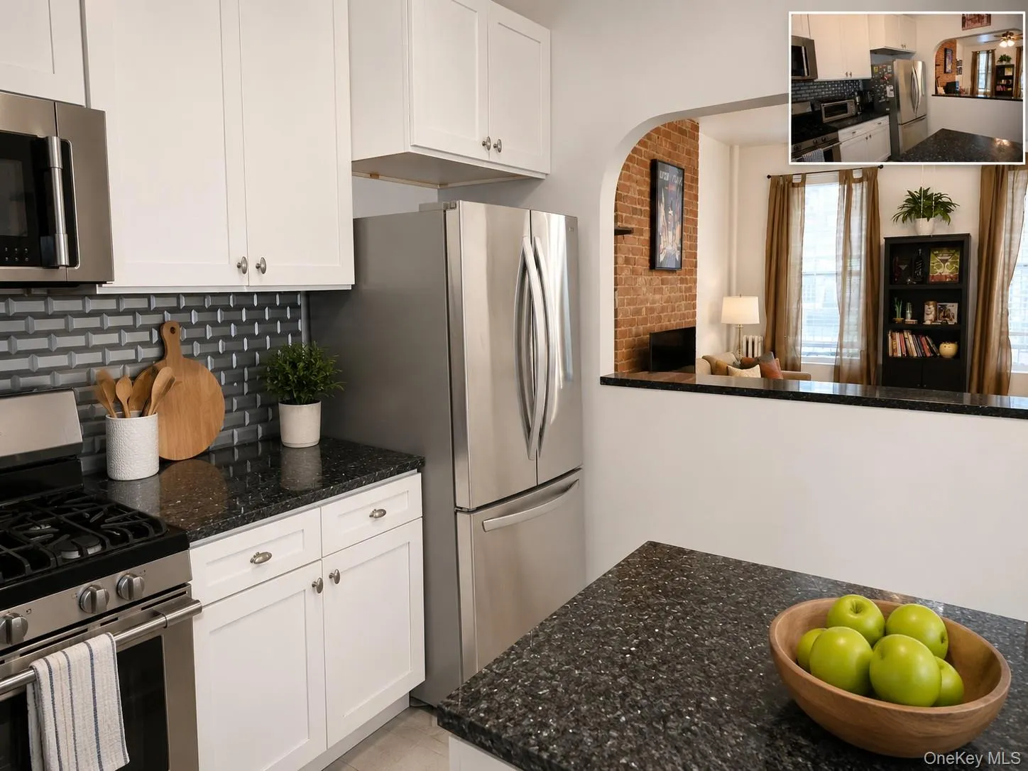 Contemporary kitchen featuring white cabinetry, dark speckled countertops, and a gray subway tile backsplash (virtually staged) Contemporary kitchen featuring white cabinetry, dark speckled countertops, and a gray subway tile backsplash (virtually staged)