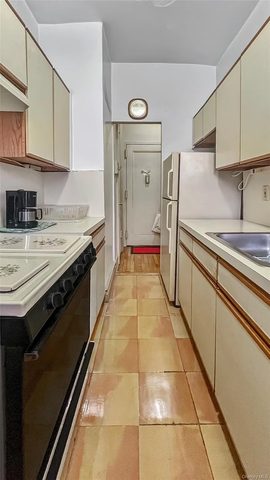Kitchen featuring sink, black range, cream cabinetry, and light tile patterned flooring Kitchen featuring sink, black range, cream cabinetry, and light tile patterned flooring