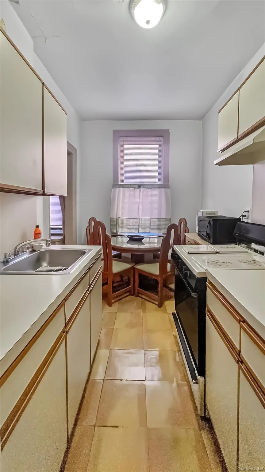 Kitchen featuring light tile patterned flooring, sink, white cabinets, and black appliances Kitchen featuring light tile patterned flooring, sink, white cabinets, and black appliances