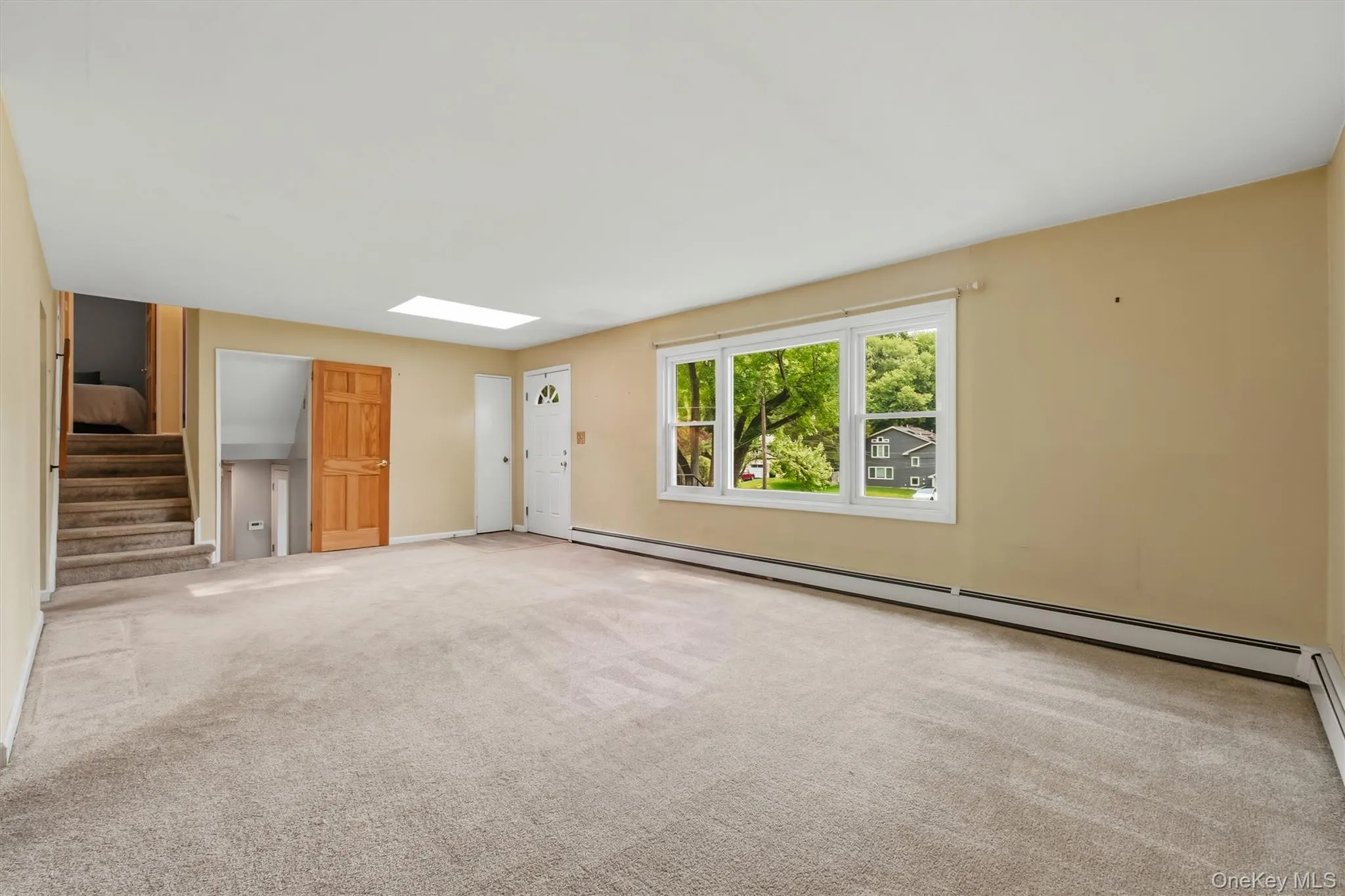 View of living room leading to upstairs bedrooms and downstairs basement area. Hardwood floors believed to be located under most of the carpeting. View of living room leading to upstairs bedrooms and downstairs basement area. Hardwood floors believed to be located under most of the carpeting.