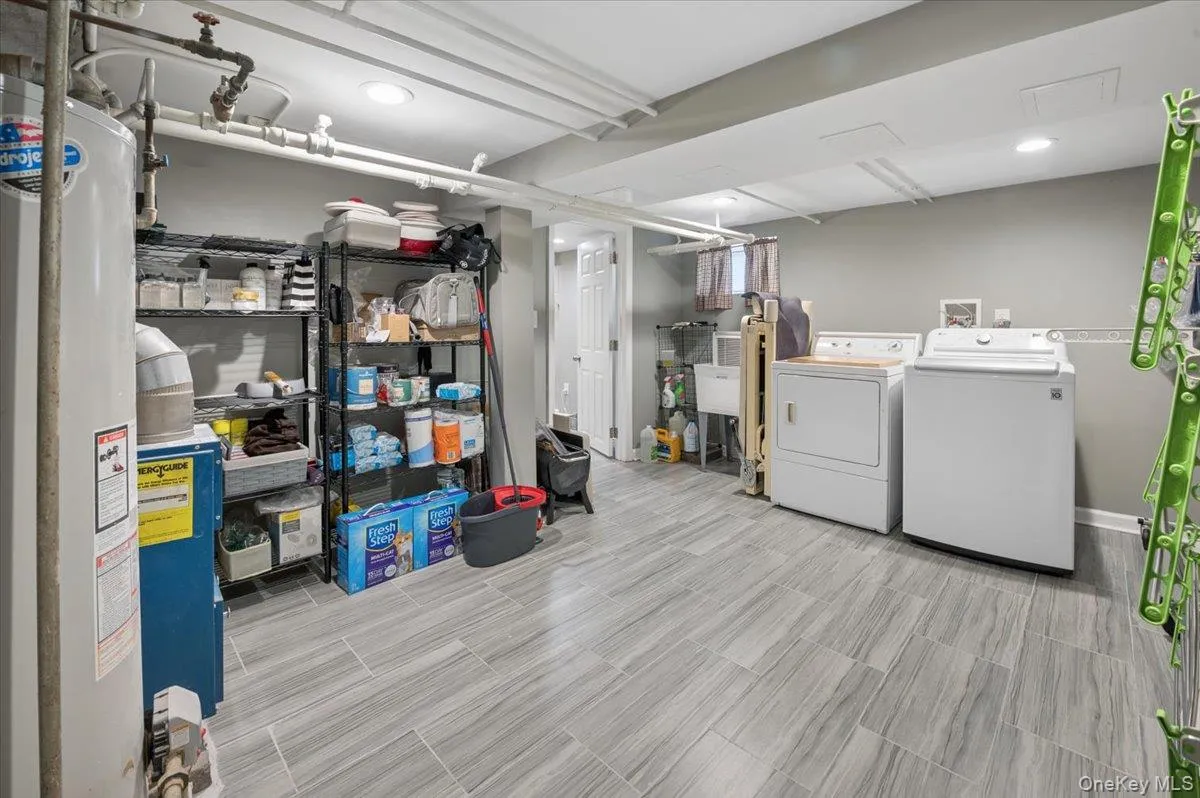 Spacious utility room featuring large-format tile flooring, a dedicated laundry area with white appliances, a utility sink, and recessed lighting Spacious utility room featuring large-format tile flooring, a dedicated laundry area with white appliances, a utility sink, and recessed lighting