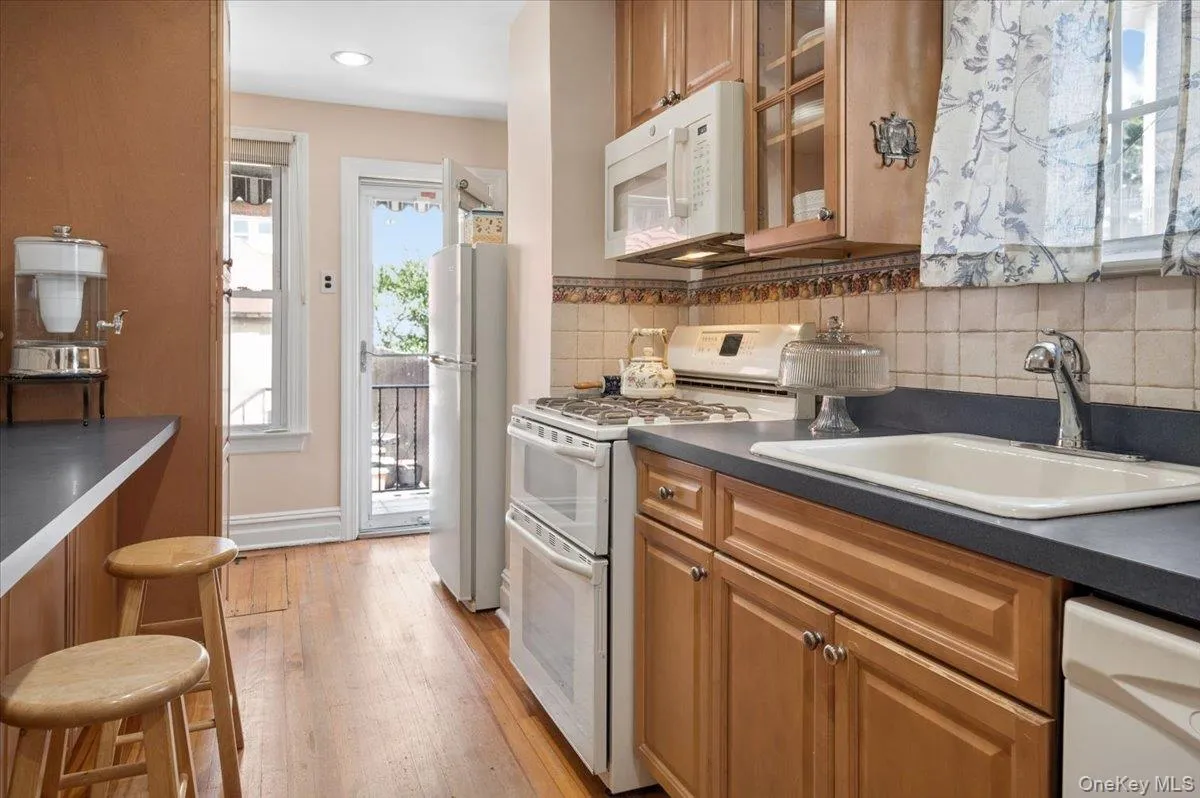 Kitchen featuring dry bar, wood-finish flooring, light wood cabinetry, a double oven range, dishwasher, and a built-in microwave. Kitchen featuring dry bar, wood-finish flooring, light wood cabinetry, a double oven range, dishwasher, and a built-in microwave.