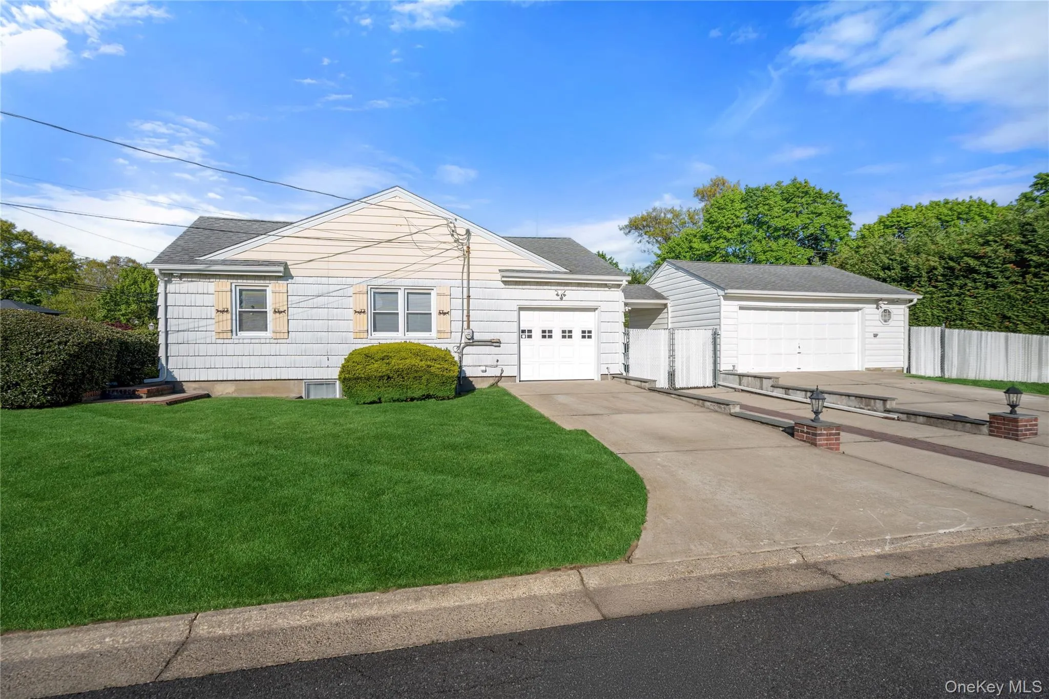 Gabled residence featuring white siding, a manicured front lawn, and attached garage Gabled residence featuring white siding, a manicured front lawn, and attached garage