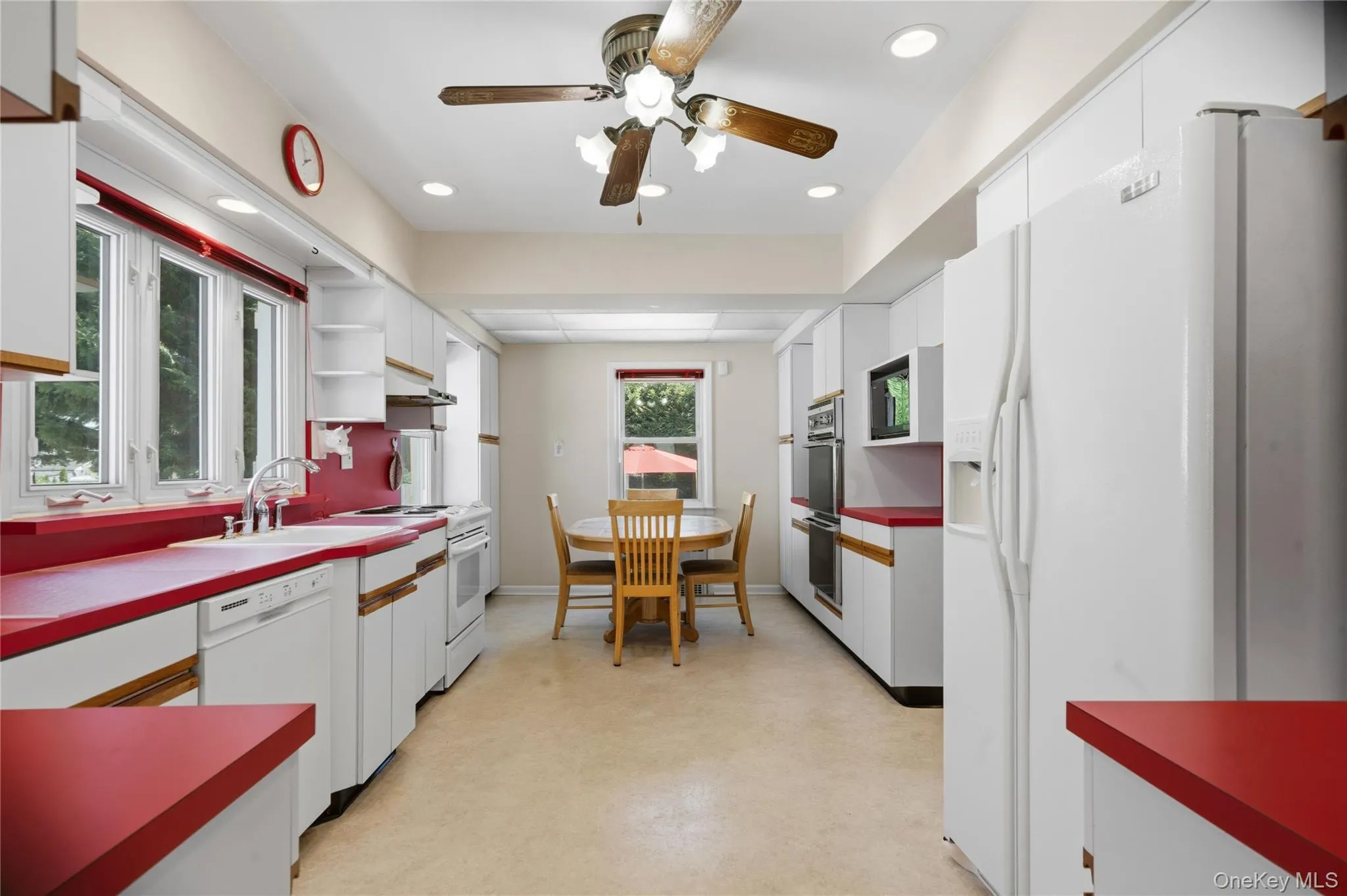Galley kitchen featuring white cabinetry, red countertops, dual wall ovens, and a built-in microwave Galley kitchen featuring white cabinetry, red countertops, dual wall ovens, and a built-in microwave
