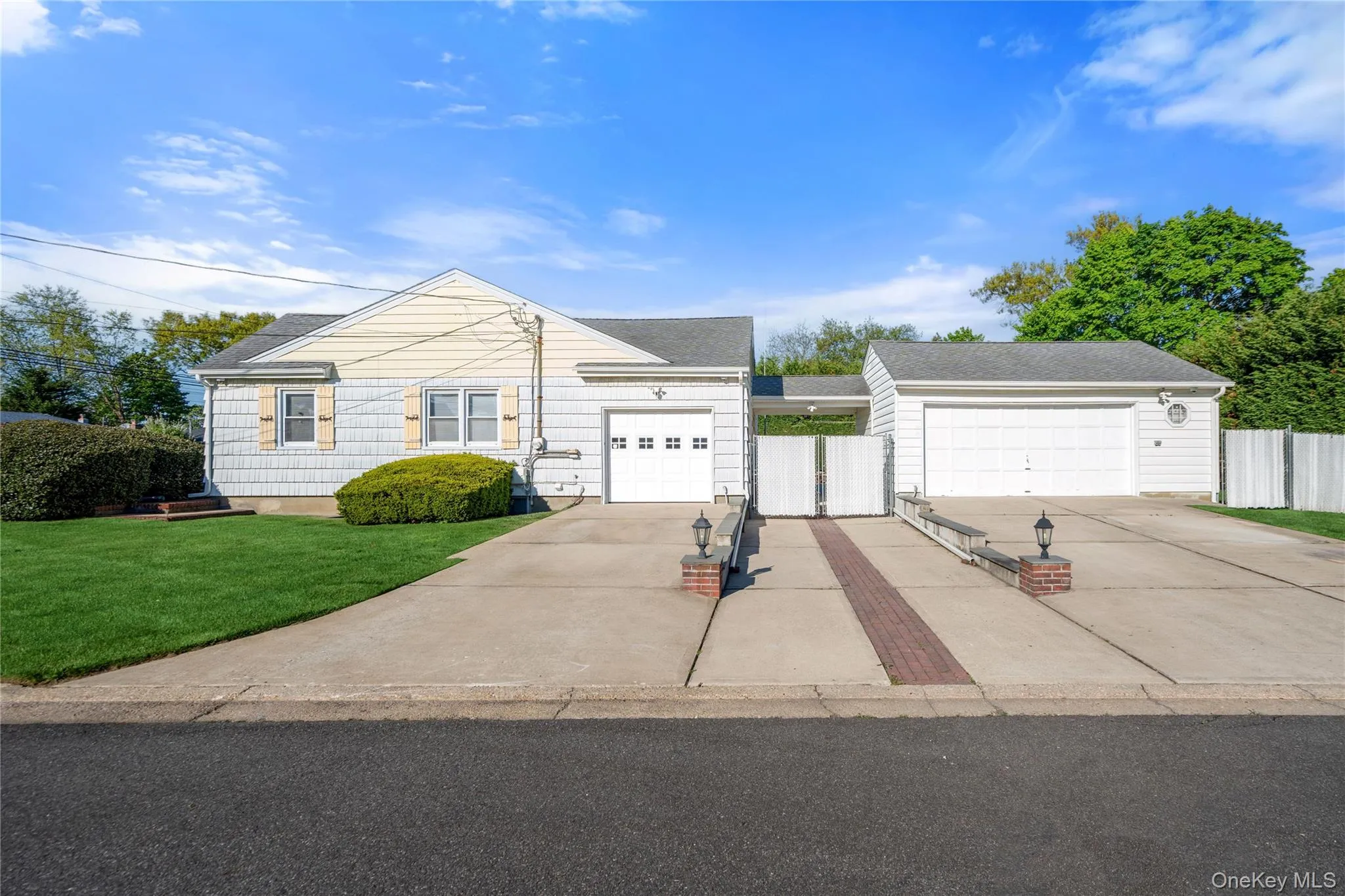 Expansive concrete driveway featuring brick accents and decorative lampposts Expansive concrete driveway featuring brick accents and decorative lampposts