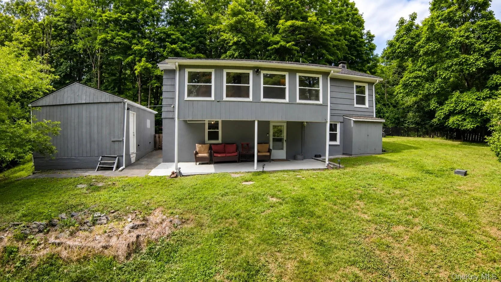 Expansive rear yard featuring mature trees, a lower-level patio, and attched utility shed Expansive rear yard featuring mature trees, a lower-level patio, and attched utility shed