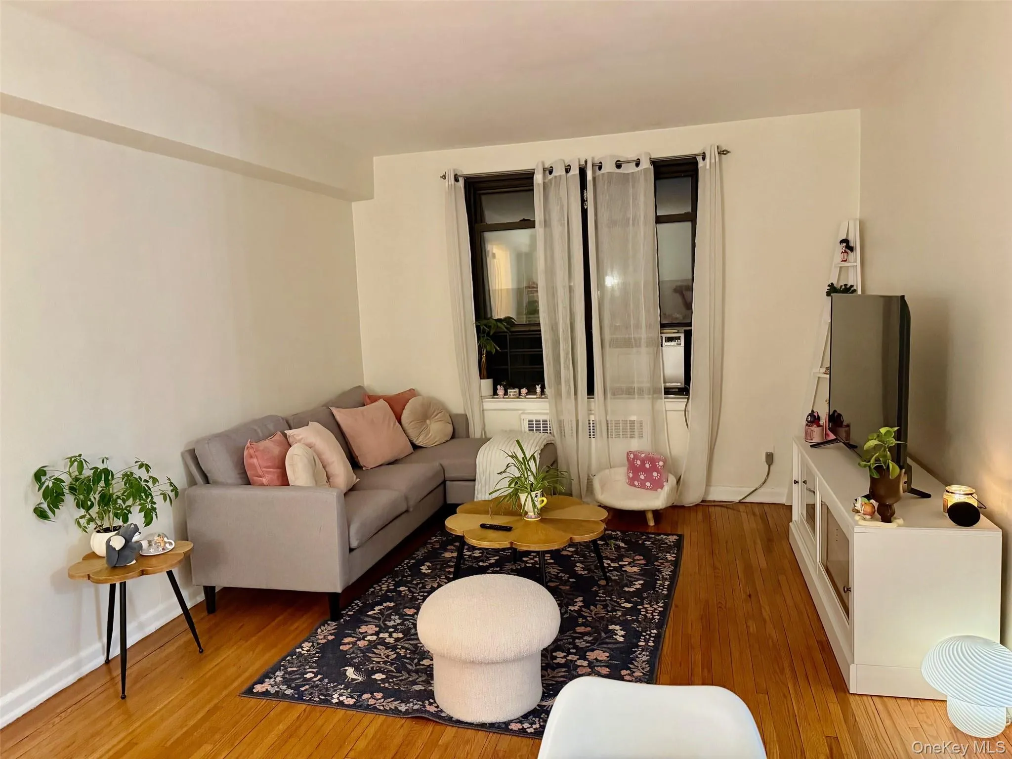 Living space featuring natural light, hardwood finish flooring, and large window. Living space featuring natural light, hardwood finish flooring, and large window.