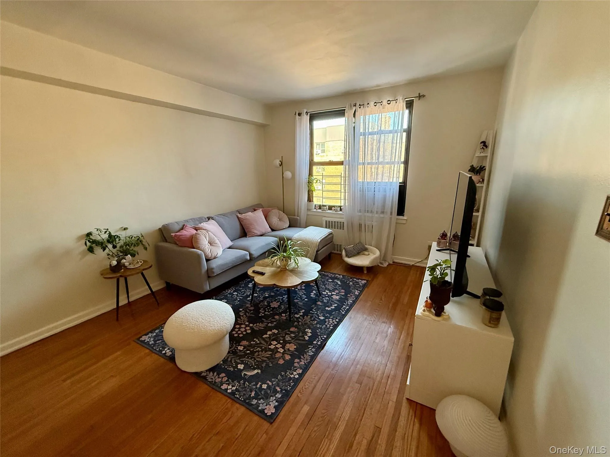Living space featuring natural light, hardwood finish flooring, and large window. Living space featuring natural light, hardwood finish flooring, and large window.