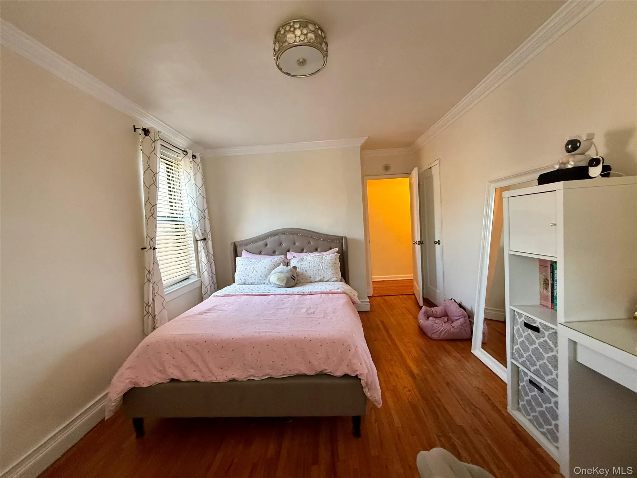 Room featuring hardwood finish flooring, two opposite side windows, crown molding, baseboards, and a semi-flush mount ceiling light fixture Room featuring hardwood finish flooring, two opposite side windows, crown molding, baseboards, and a semi-flush mount ceiling light fixture