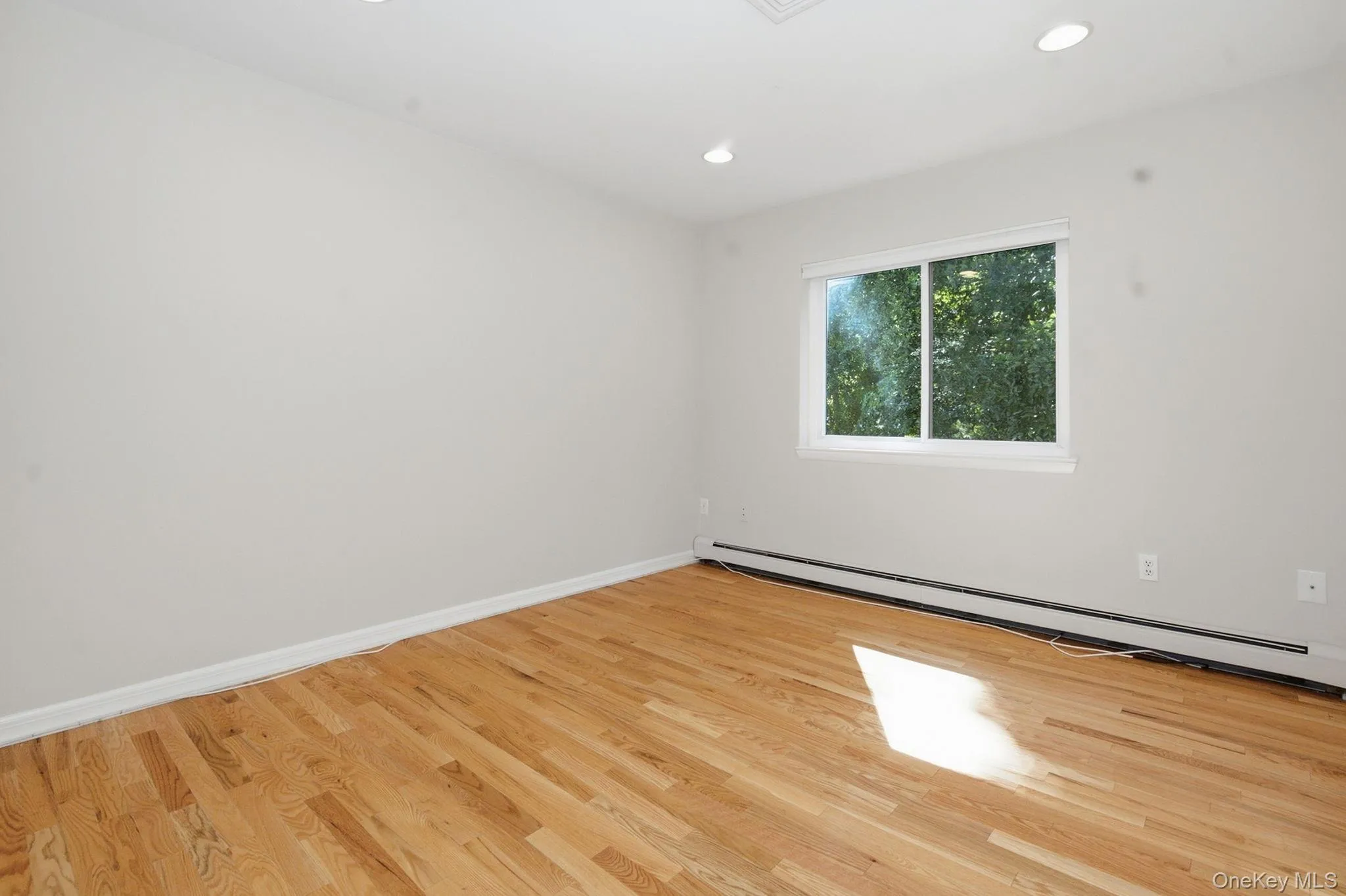 Second bedroom features a large window overlooking the surrounding greenery. Second bedroom features a large window overlooking the surrounding greenery.