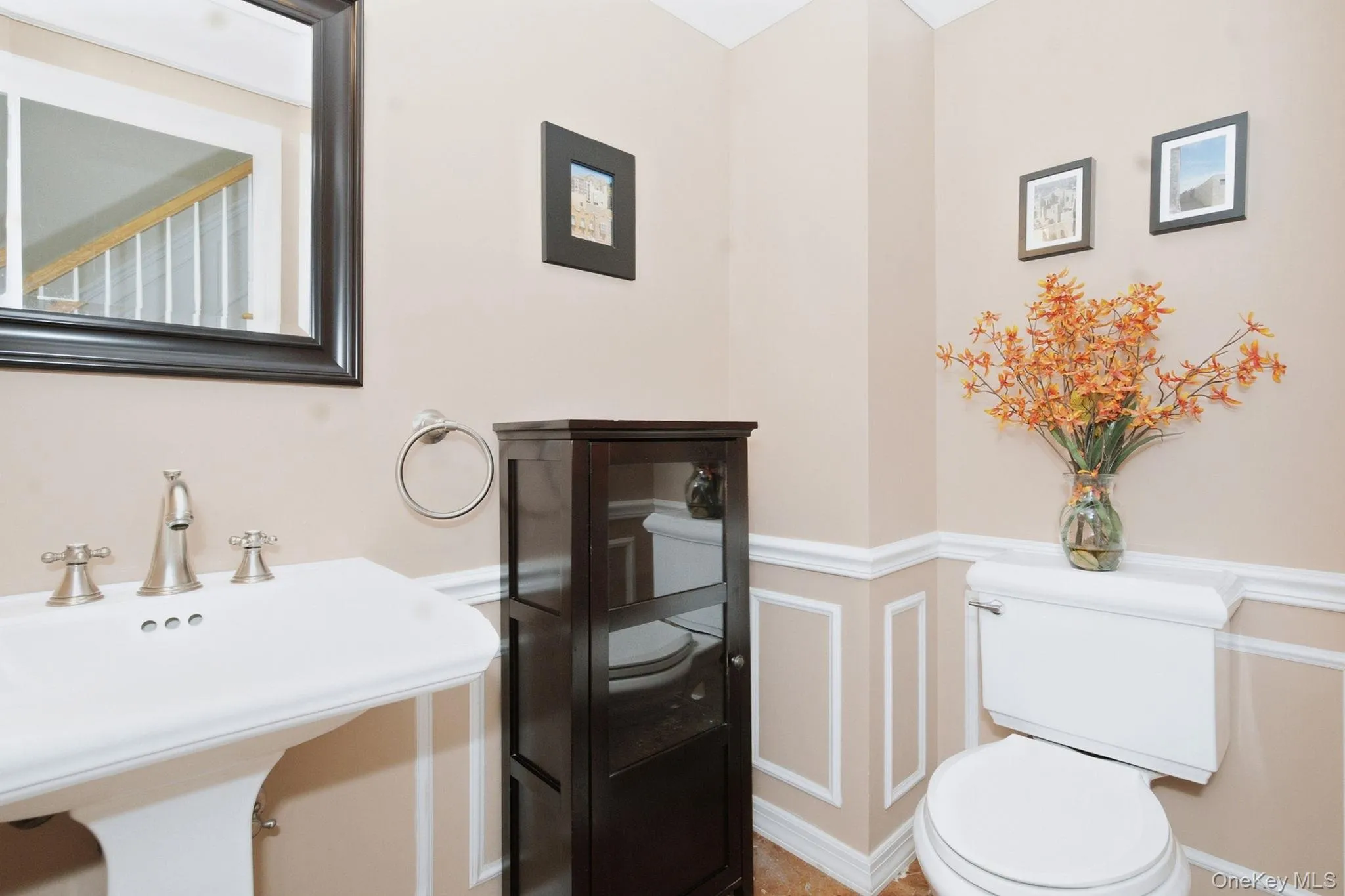 Main-level powder room features wainscoting and pedestal sink. Main-level powder room features wainscoting and pedestal sink.