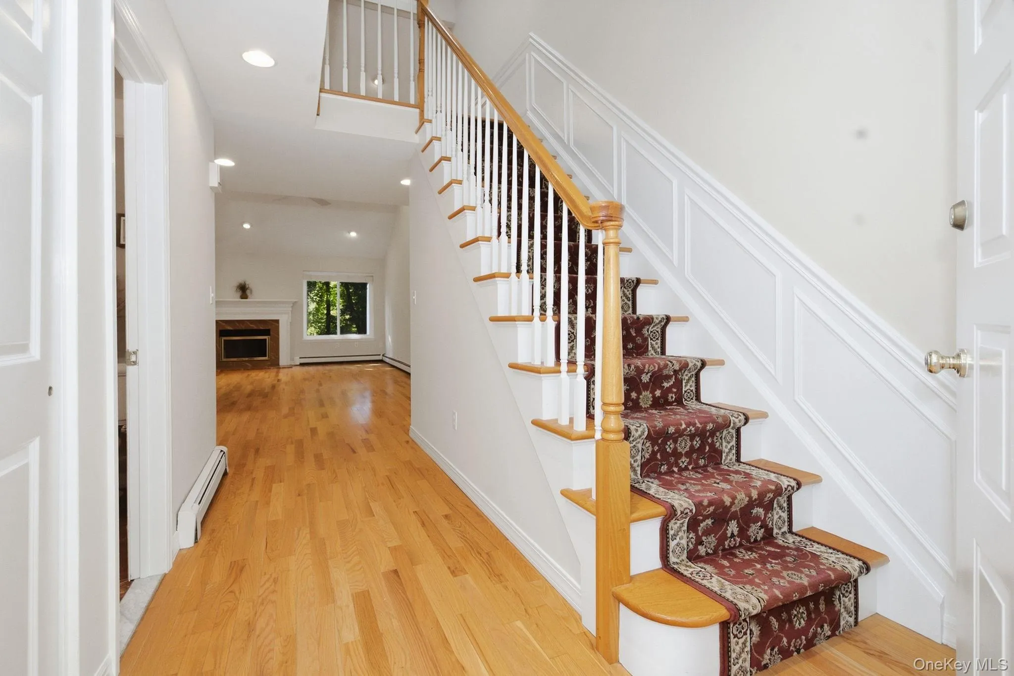 Open staircase provides a direct sightline from the entry toward the living room and fireplace. Open staircase provides a direct sightline from the entry toward the living room and fireplace.