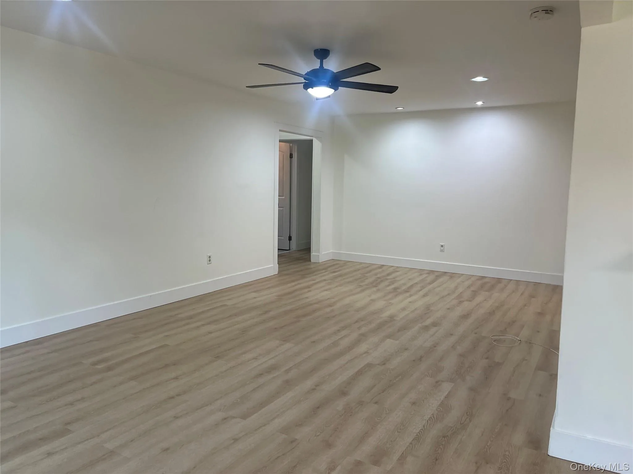 Spacious room featuring light wood-finish flooring, recessed lighting, and a contemporary ceiling fan Spacious room featuring light wood-finish flooring, recessed lighting, and a contemporary ceiling fan