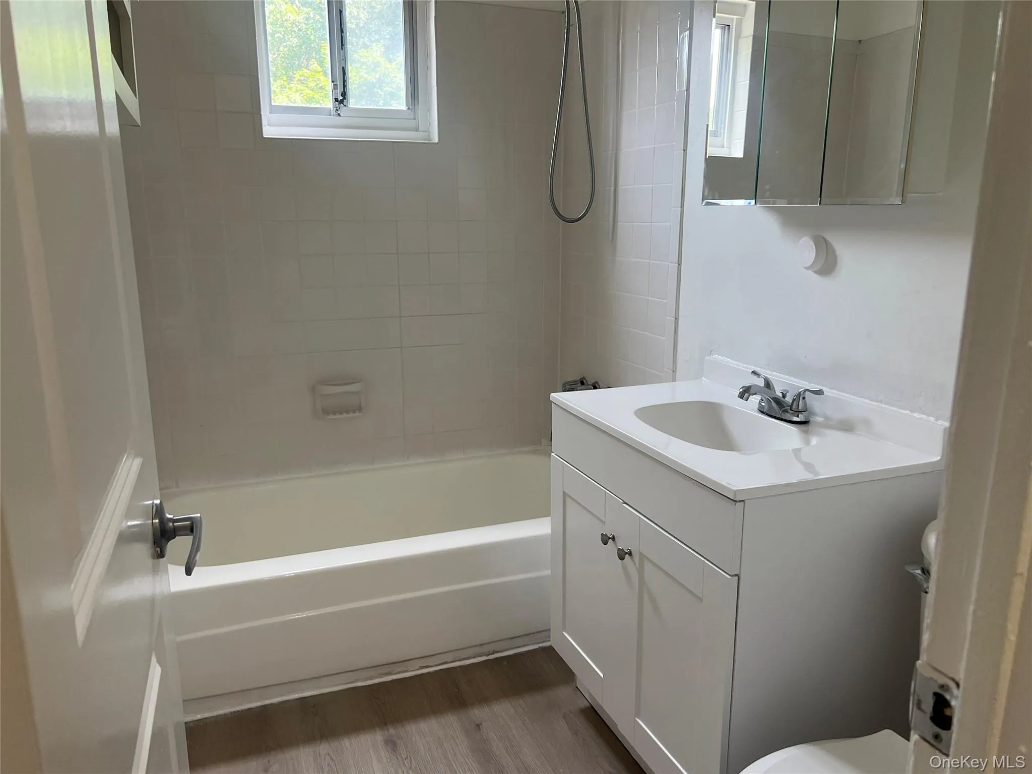 Bathroom featuring a white vanity with integrated sink, chrome faucet, and a wall-mounted medicine cabinet Bathroom featuring a white vanity with integrated sink, chrome faucet, and a wall-mounted medicine cabinet
