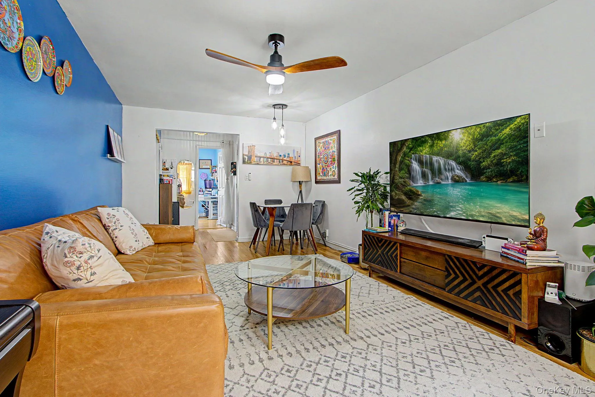 Spacious living area featuring a ceiling fan and wood-finish flooring Spacious living area featuring a ceiling fan and wood-finish flooring