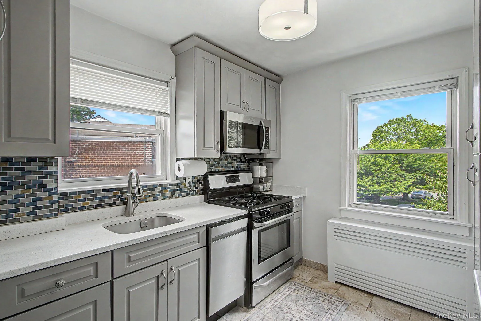 Kitchen featuring cabinetry, mosaic tile backsplash, stainless steel appliances, and a stainless steel sink with a chrome faucet Kitchen featuring cabinetry, mosaic tile backsplash, stainless steel appliances, and a stainless steel sink with a chrome faucet