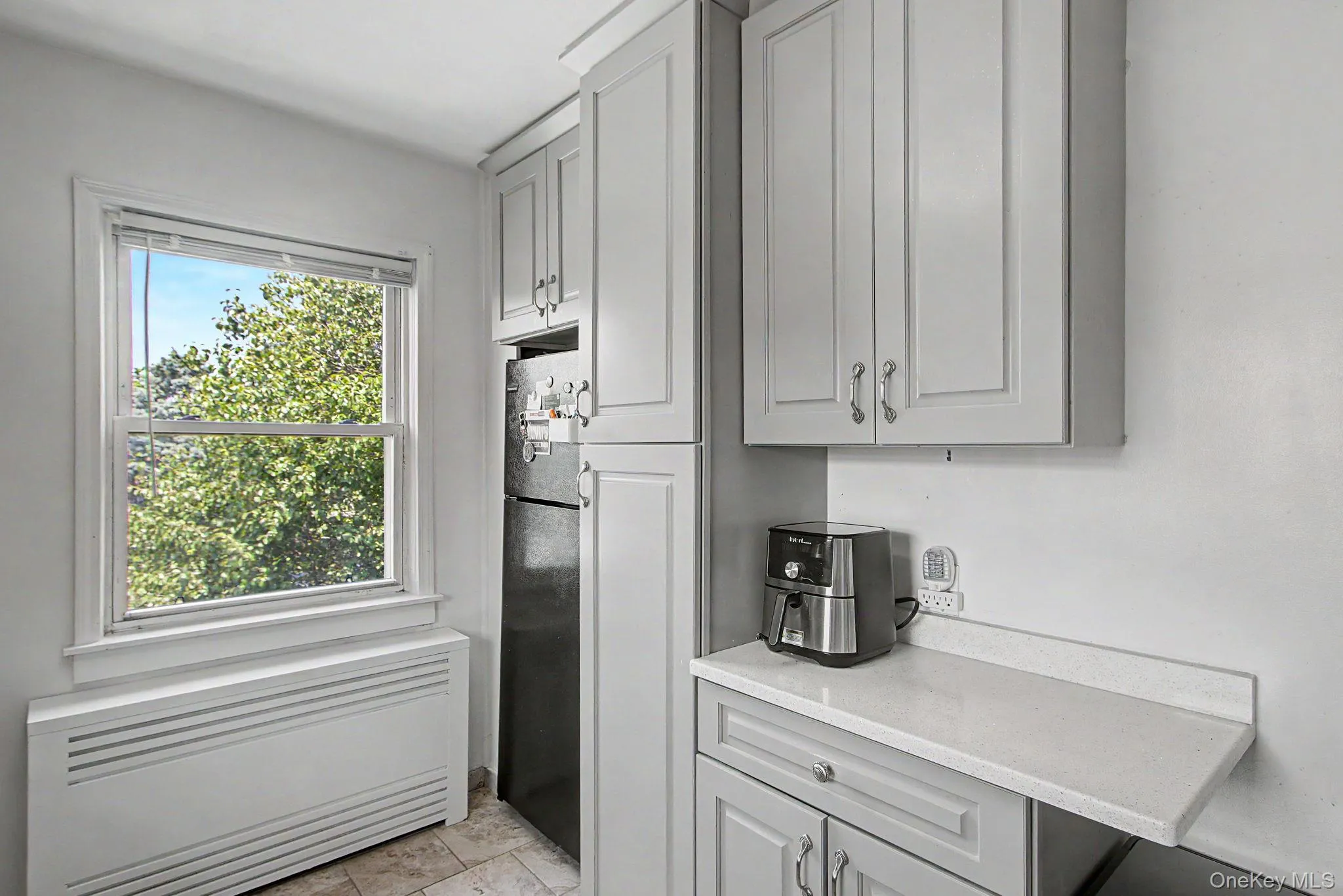 Kitchen area featuring light-toned cabinetry, a built-in refrigerator, white countertops, and tiled flooring Kitchen area featuring light-toned cabinetry, a built-in refrigerator, white countertops, and tiled flooring