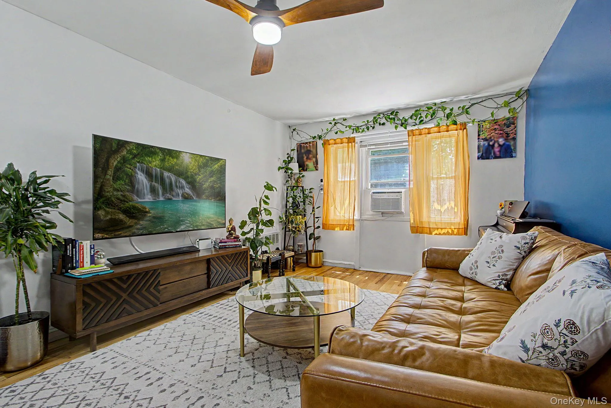 Living area featuring light wood-finish flooring and a ceiling fan with integrated lighting Living area featuring light wood-finish flooring and a ceiling fan with integrated lighting