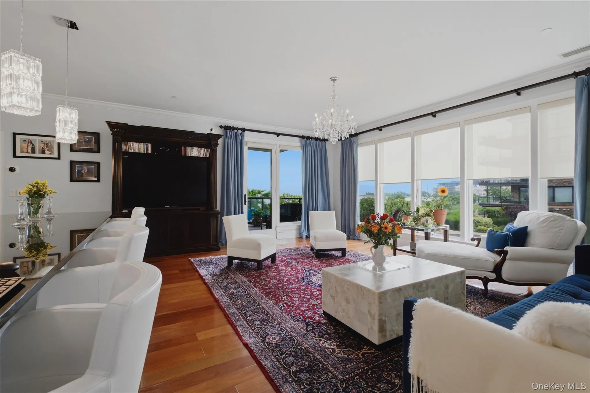 Sun-filled living area with walls of windows, patio access, and picturesque views beyond Sun-filled living area with walls of windows, patio access, and picturesque views beyond