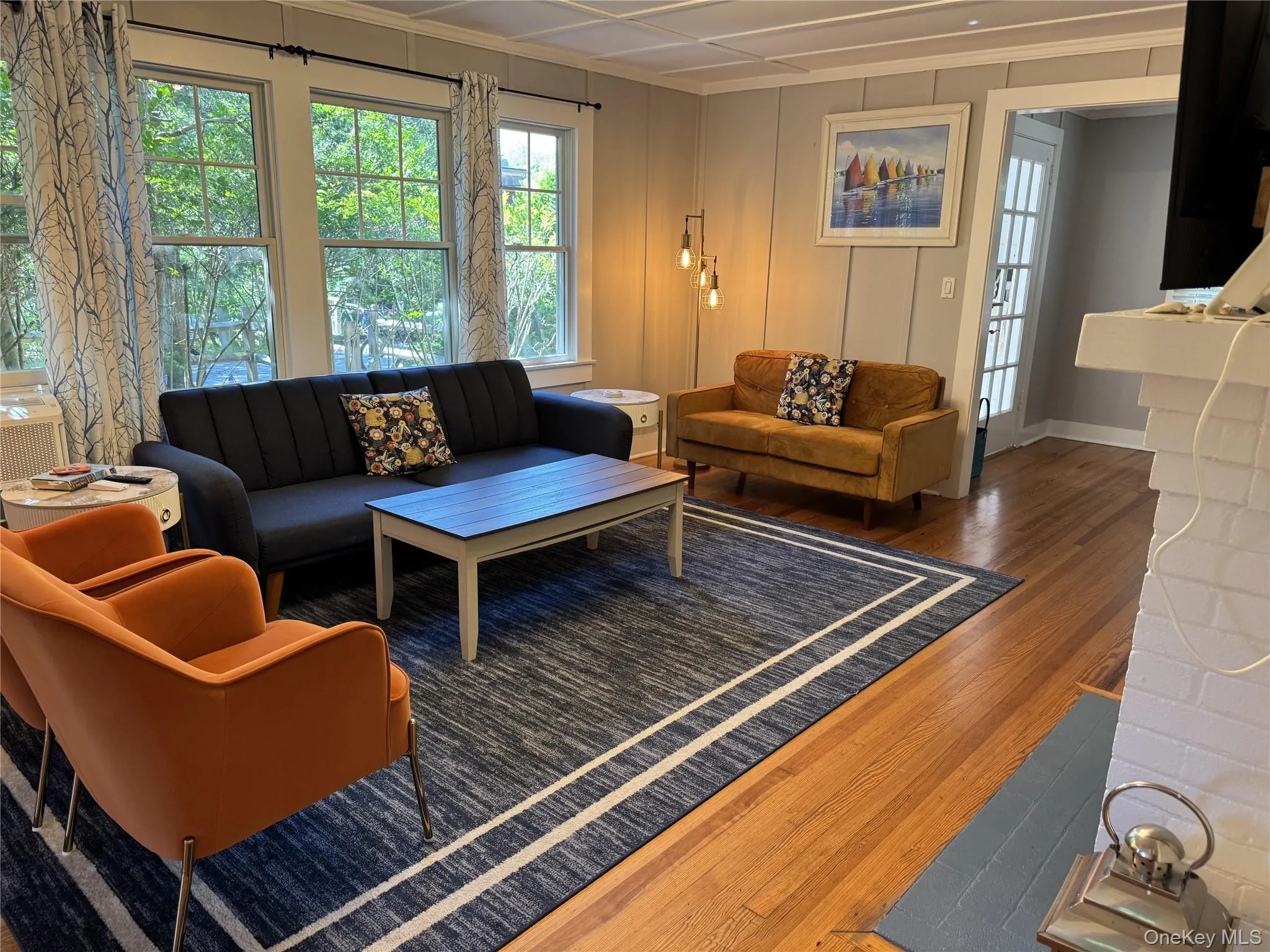 Living room with wood finished floors, healthy amount of natural light, ornamental molding, and a chandelier Living room with wood finished floors, healthy amount of natural light, ornamental molding, and a chandelier