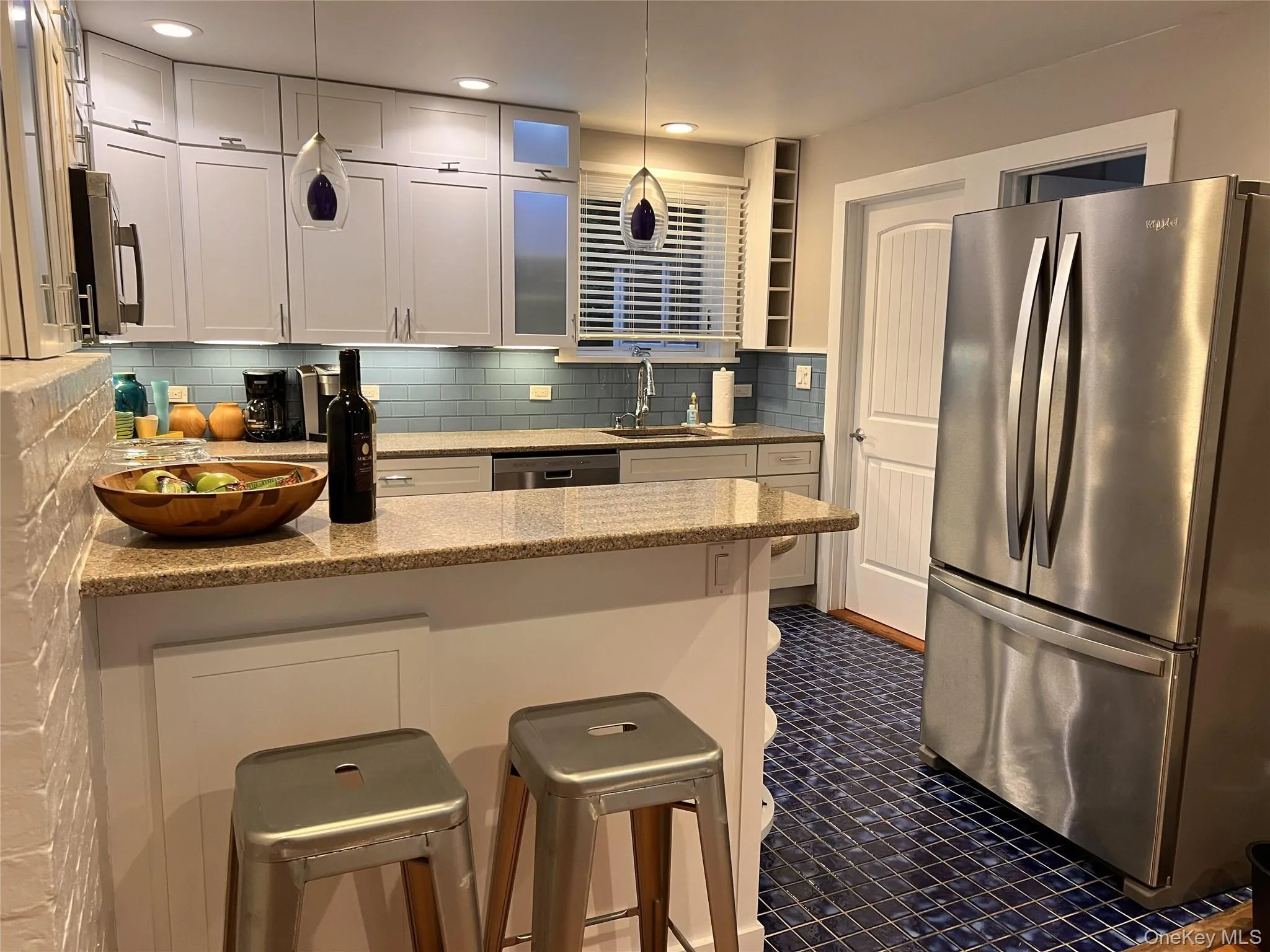 Kitchen with a peninsula, stainless steel appliances, a kitchen bar, decorative backsplash, and light stone countertops Kitchen with a peninsula, stainless steel appliances, a kitchen bar, decorative backsplash, and light stone countertops