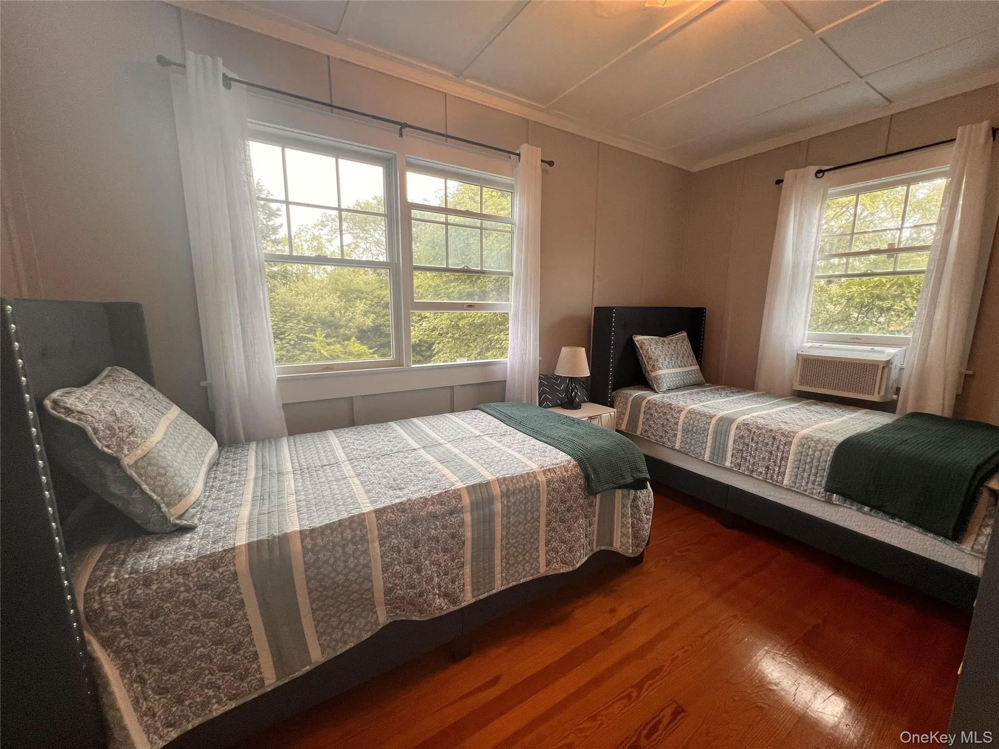 Bedroom featuring ornamental molding, wood finished floors, and a decorative wall Bedroom featuring ornamental molding, wood finished floors, and a decorative wall