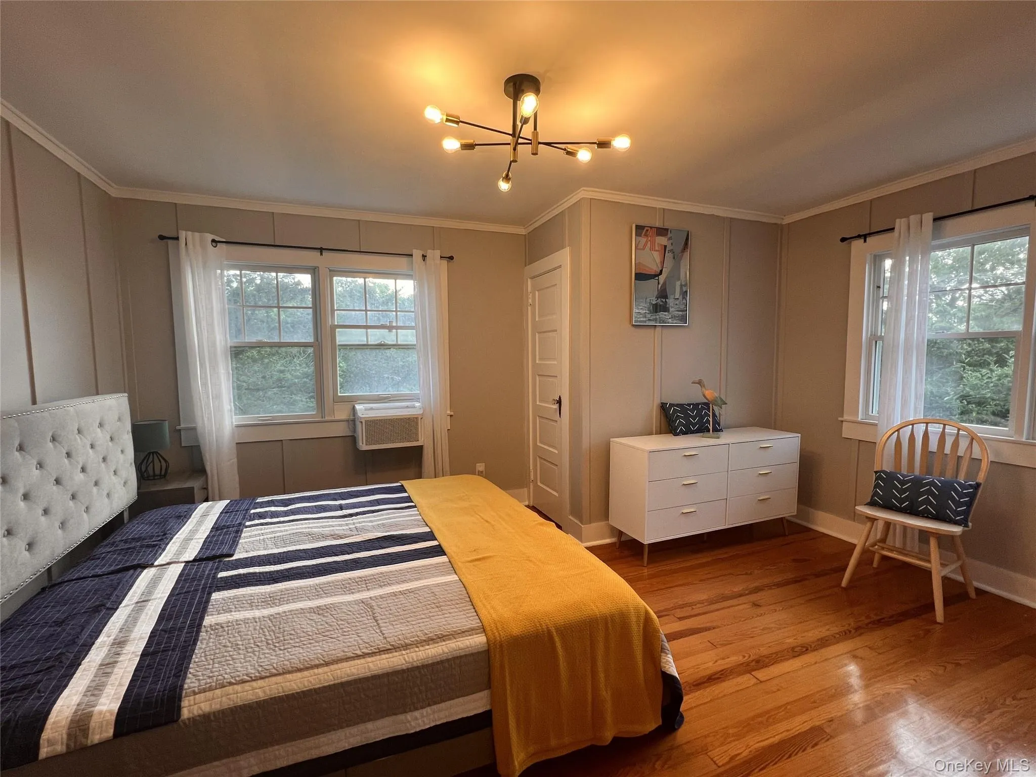 Bedroom featuring wood finished floors, a chandelier, and crown molding Bedroom featuring wood finished floors, a chandelier, and crown molding