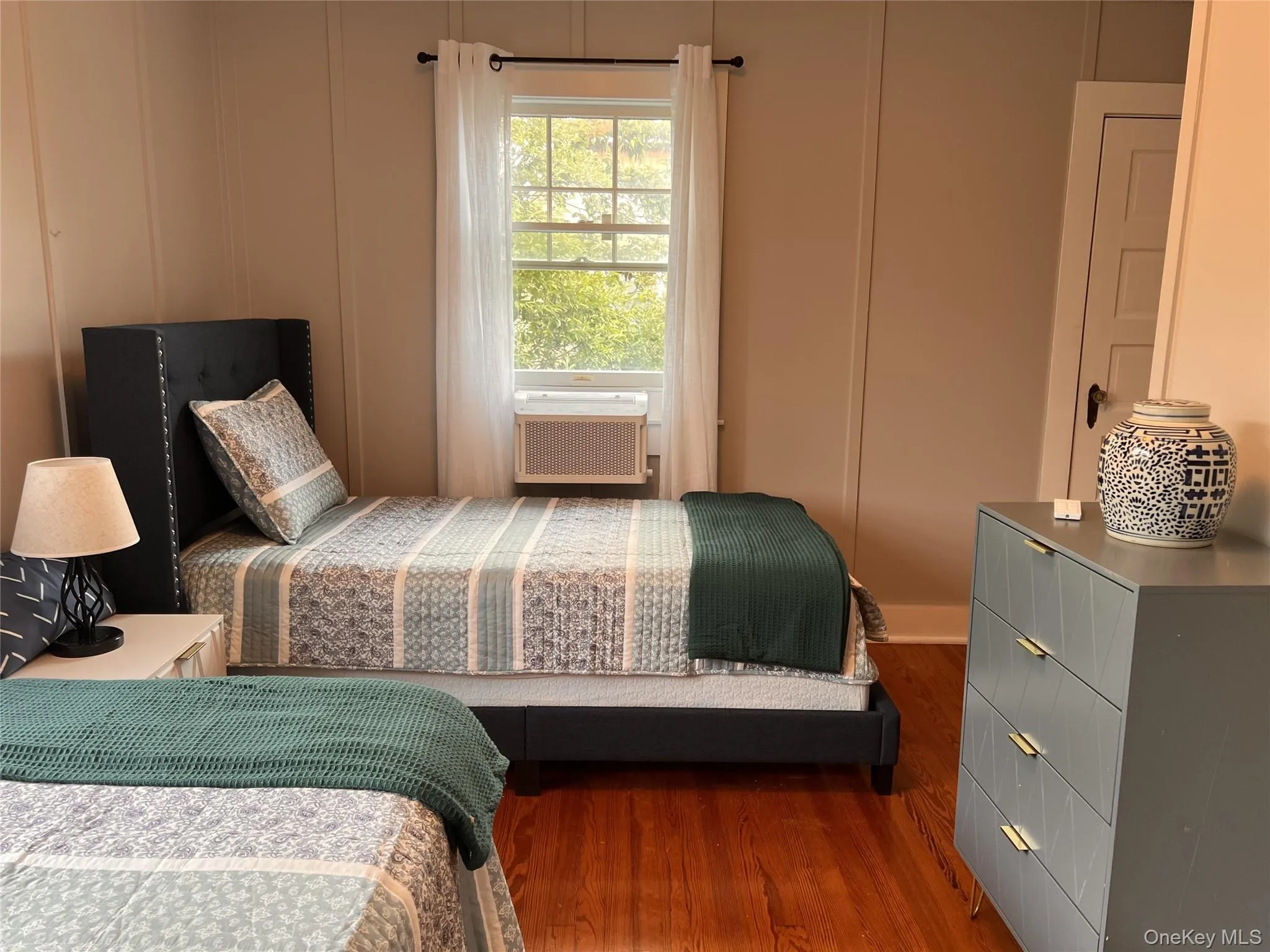 Bedroom featuring dark wood-style flooring and a decorative wall Bedroom featuring dark wood-style flooring and a decorative wall