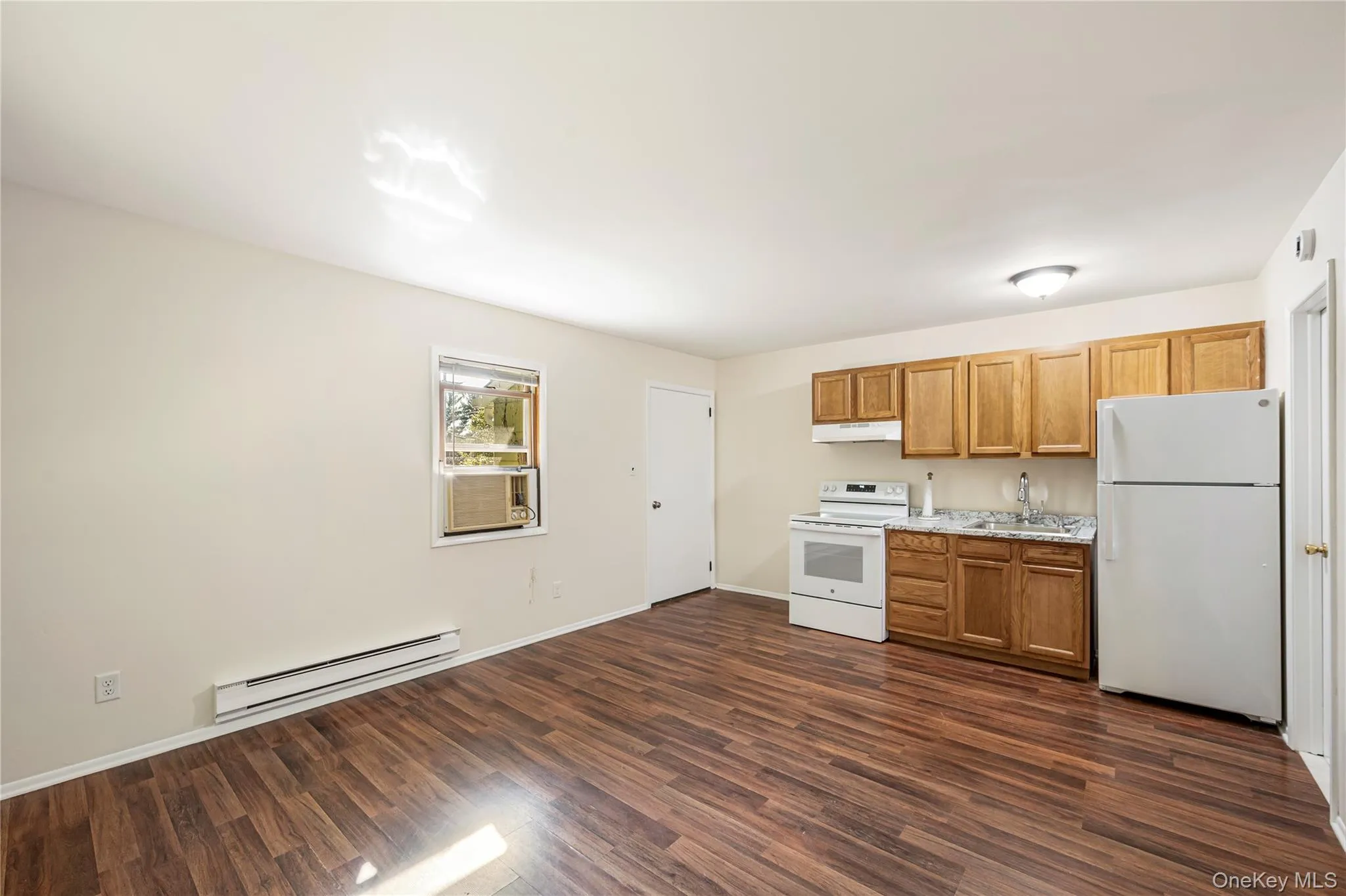 Kitchen with sink, white appliances, cooling unit, dark hardwood / wood-style floors, and a baseboard radiator Kitchen with sink, white appliances, cooling unit, dark hardwood / wood-style floors, and a baseboard radiator