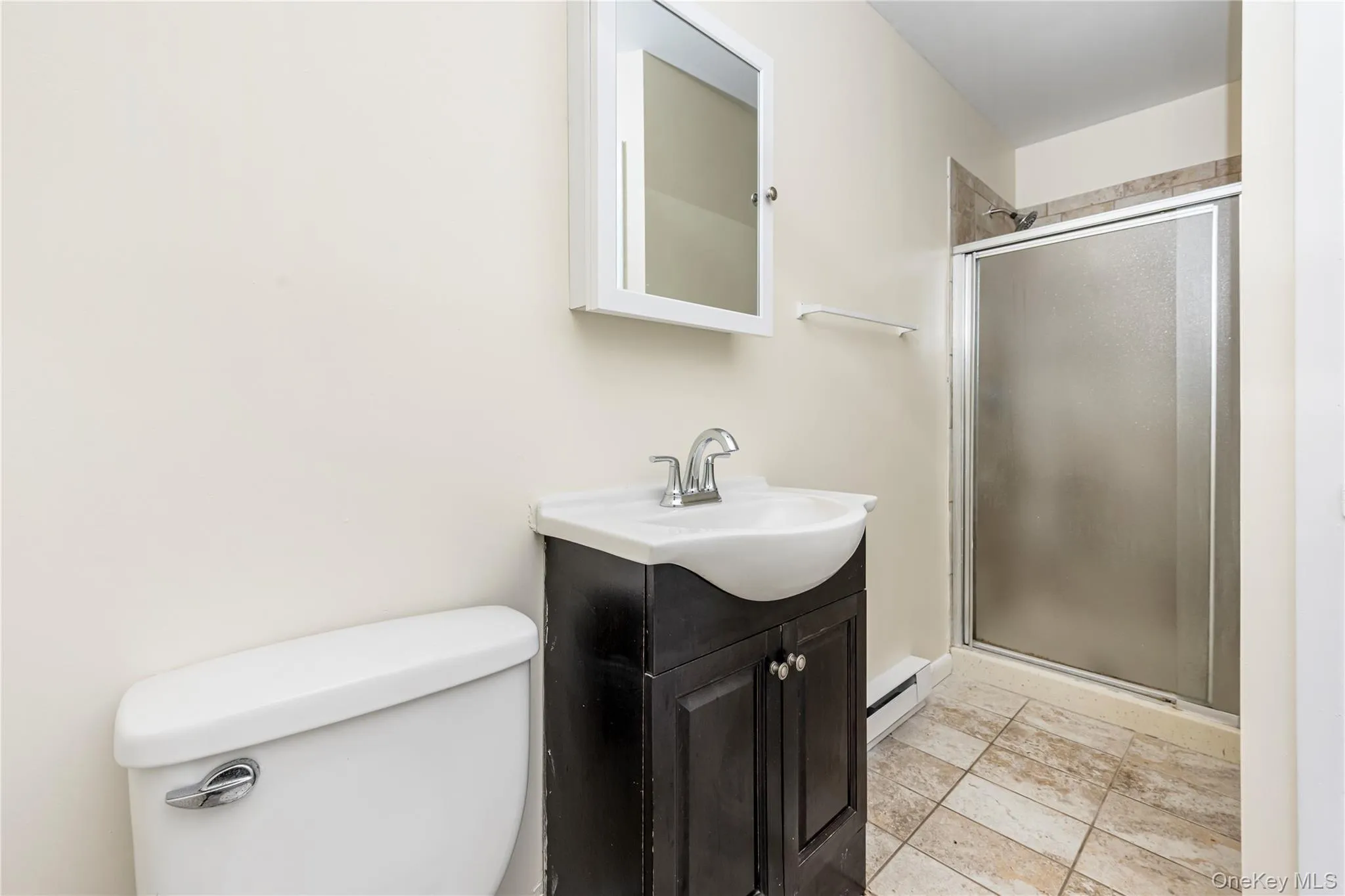 Bathroom with baseboard heating, vanity, toilet, and an enclosed shower Bathroom with baseboard heating, vanity, toilet, and an enclosed shower