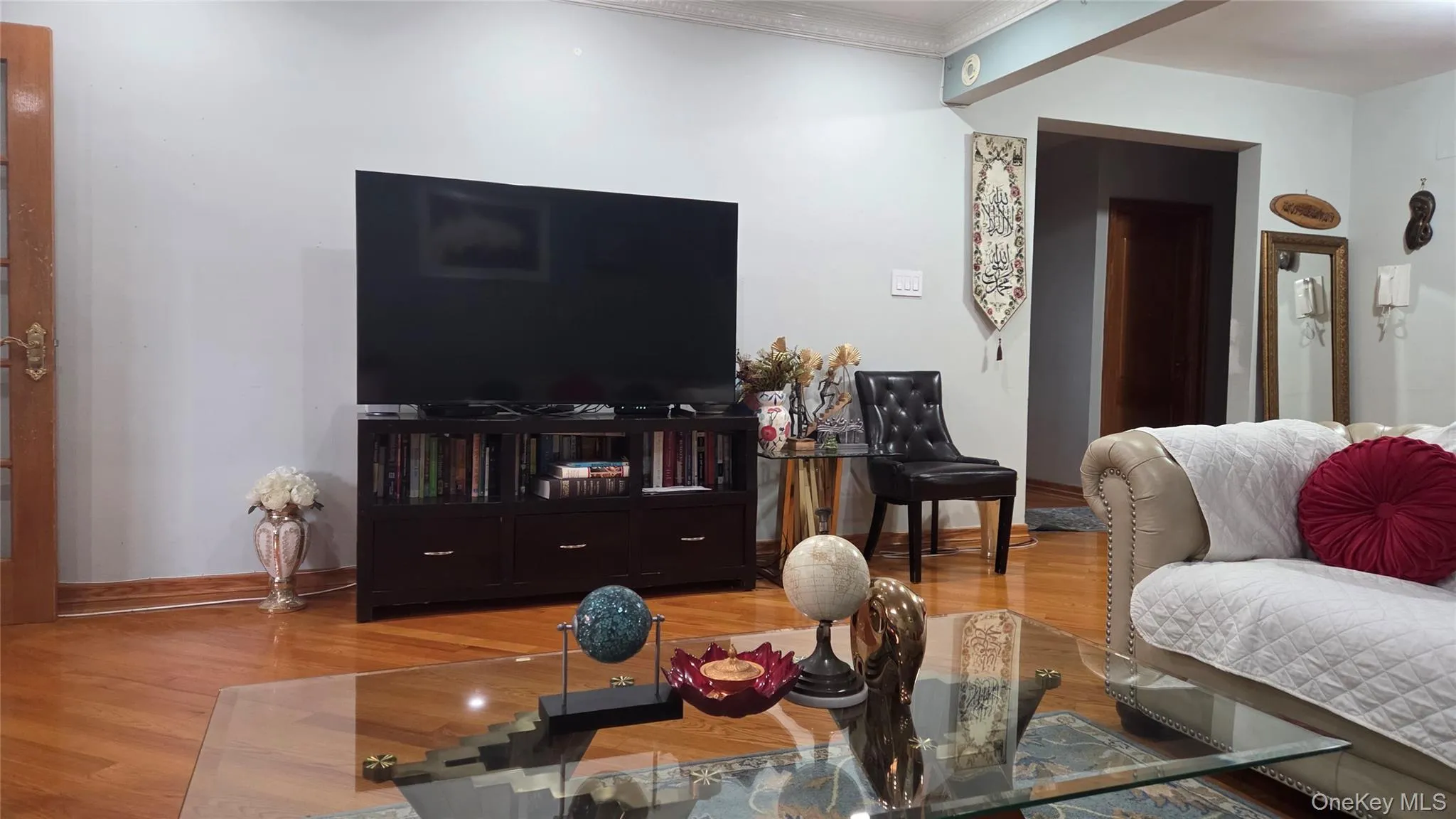 Spacious living area featuring wood-finish flooring, a neutral color palette, and an open doorway leading to an interior room Spacious living area featuring wood-finish flooring, a neutral color palette, and an open doorway leading to an interior room