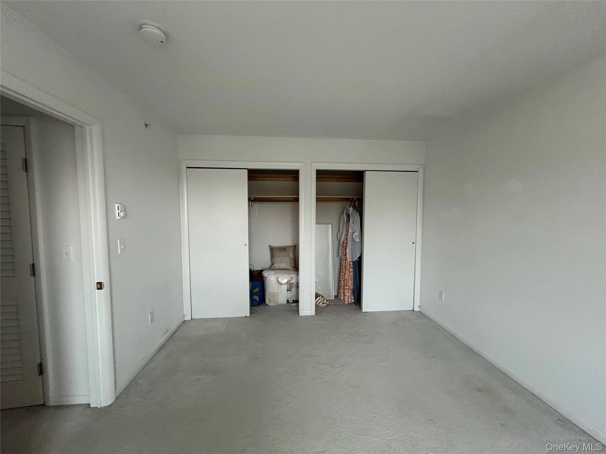 Unfurnished bedroom with multiple closets and concrete floors Unfurnished bedroom with multiple closets and concrete floors